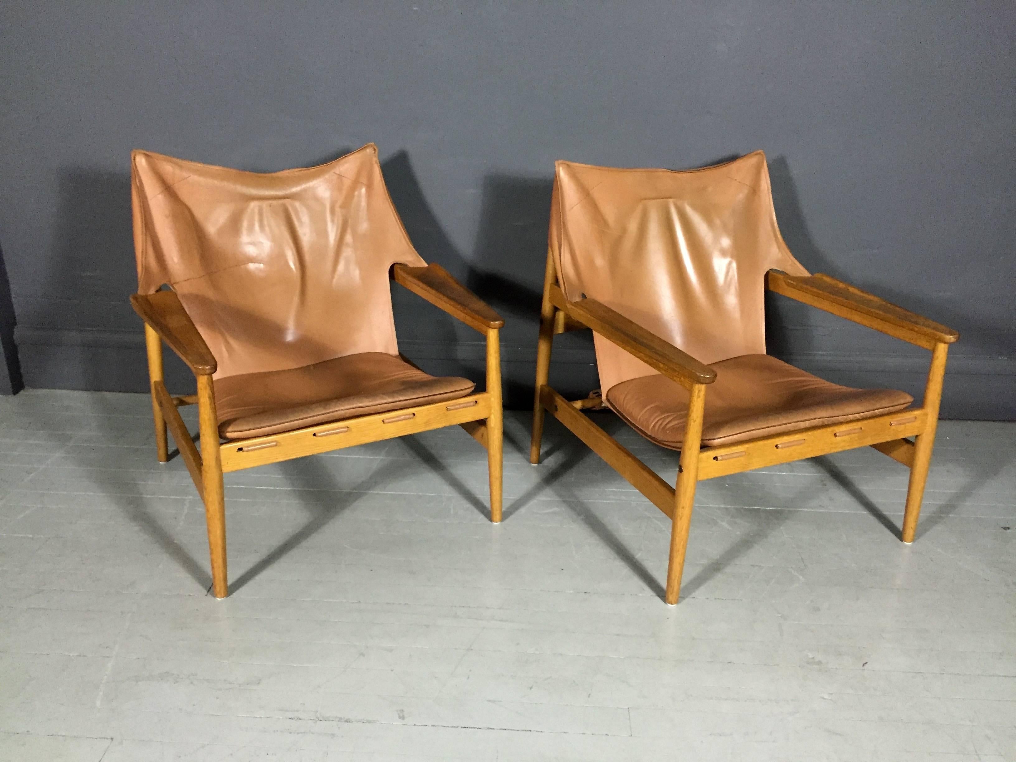 Spectacular pair of sling or safari chairs in rare tan all-leather with oak frames, contoured arms, lightly cushioned loose seat, fitted leather back with three-buckle support. Hans Olsen for Viskadalens Möbelfabrik AB, Denmark, 1960s.

One chair