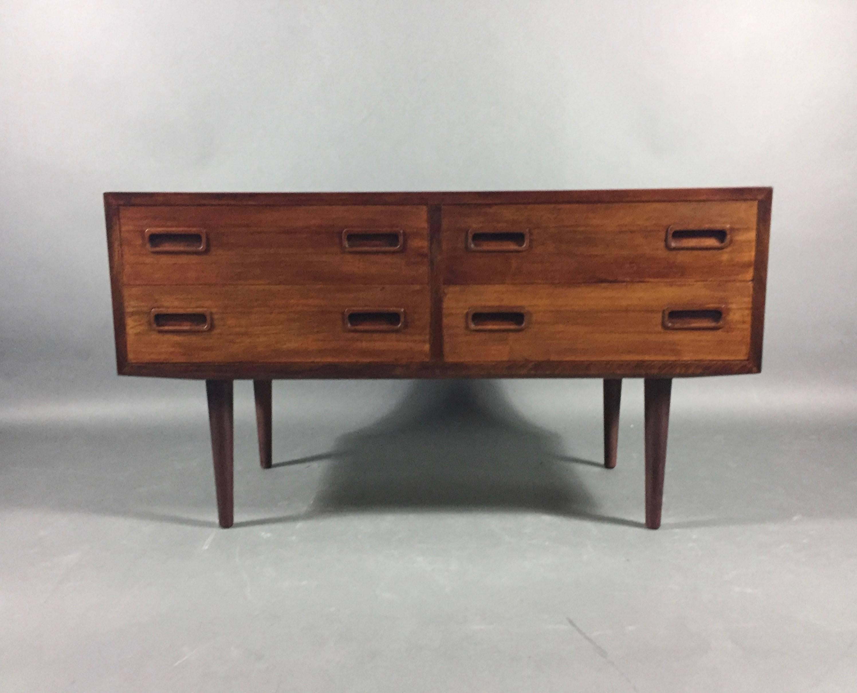 A beautiful low chest with four-drawer and carefully crafted rosewood handles over tapered legs. Striking rosewood grain pattern to top and sides. Denmark, circa 1960s. Danish control stamp to back. Excellent refinished condition. Minor veneer break
