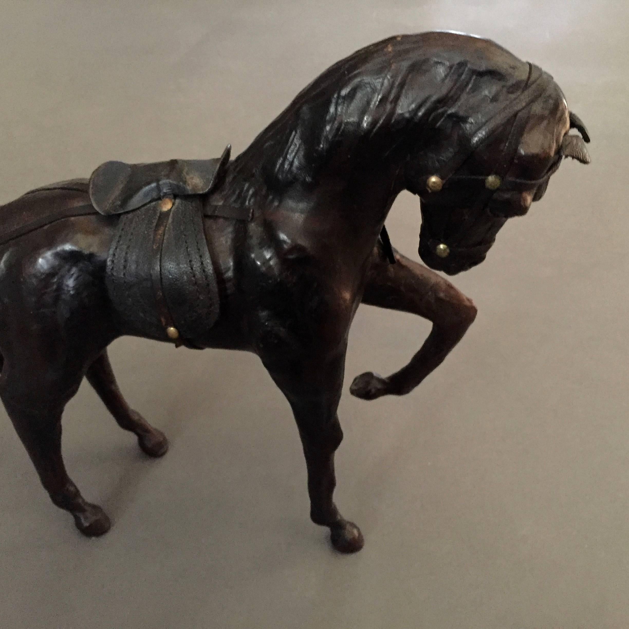 Originally designed to stand a four-wheeled trolly as a pull-toy at the turn of the century, these two full leather wrapped horse sculptures were likely produced around the 1940s and are both in terrific vintage condition, brown horse missing one