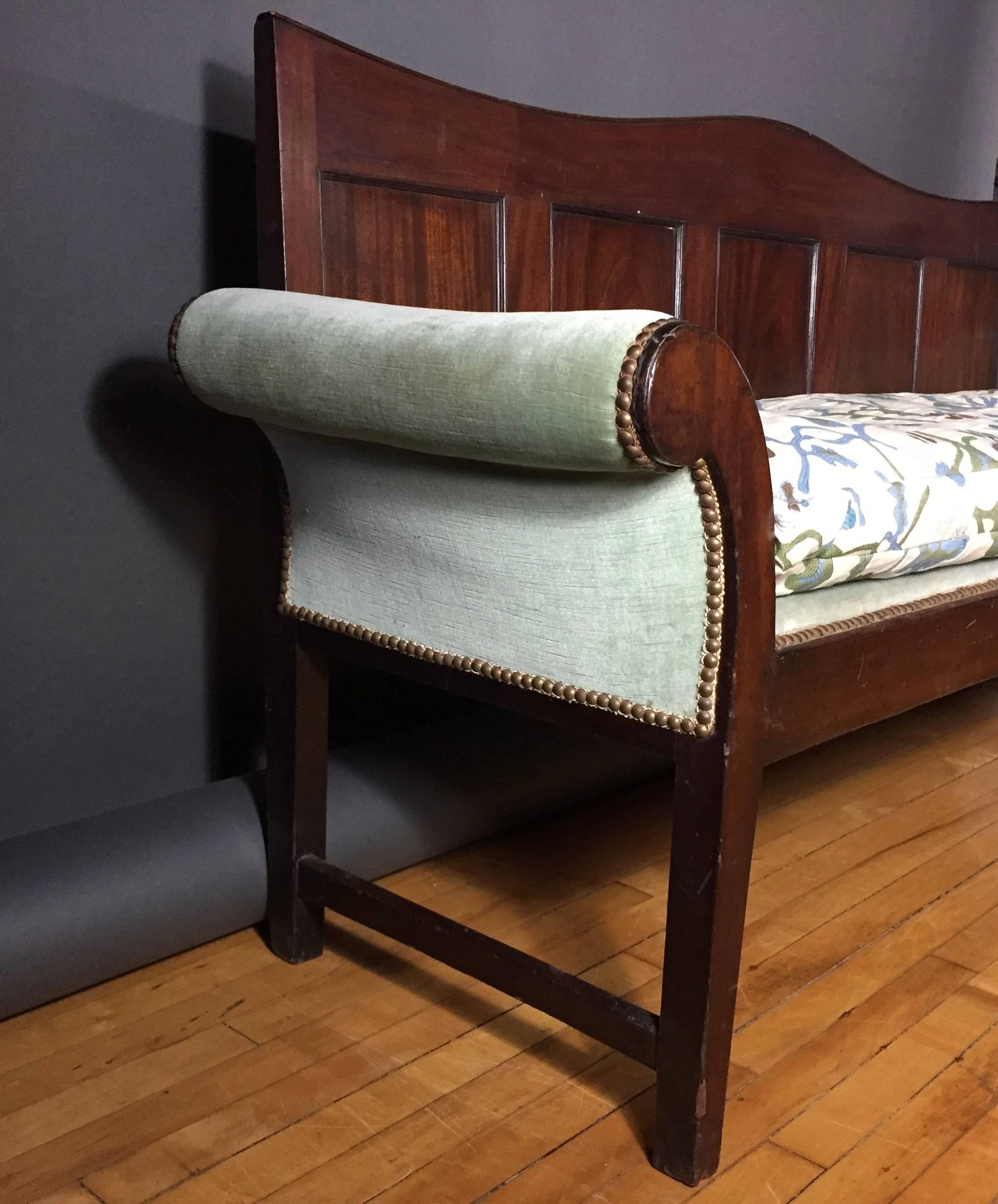 A wonderful hall bench from the late 18th century English Georgian period with panel back and scroll arms. Beautifully embroidered upholstery fabric over down wrapped cushion recently added. Minor re-gluing of panel trim.