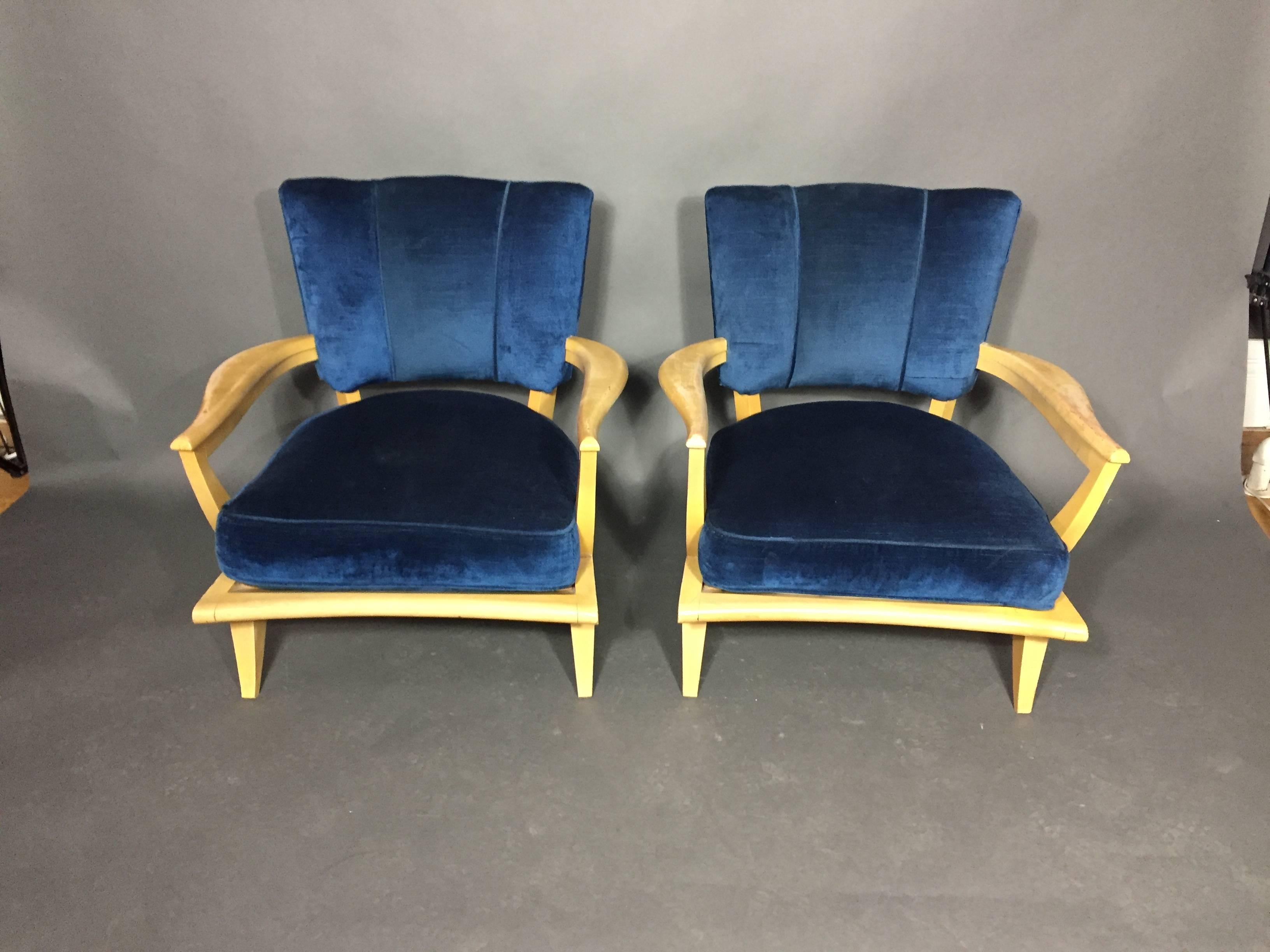 A very stylish pair of French modern lounge chairs having velvet upholstered backs and seat cushions framed by shaped arms circa 1950. Lacquered finish over mahogany frames. Some wear to finish exposing darker wood underneath great vintage feel.