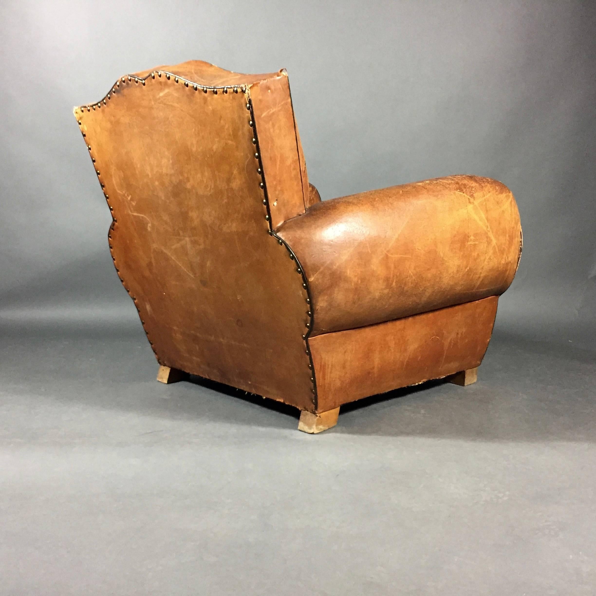 One of the iconic French leather chair designs of the late Art Deco period - this gorgeous club chair with perfectly worn leather has a black leather contrast piping and matching velvet seat cover. Brass nails trimmed in back. France, late 1930s.