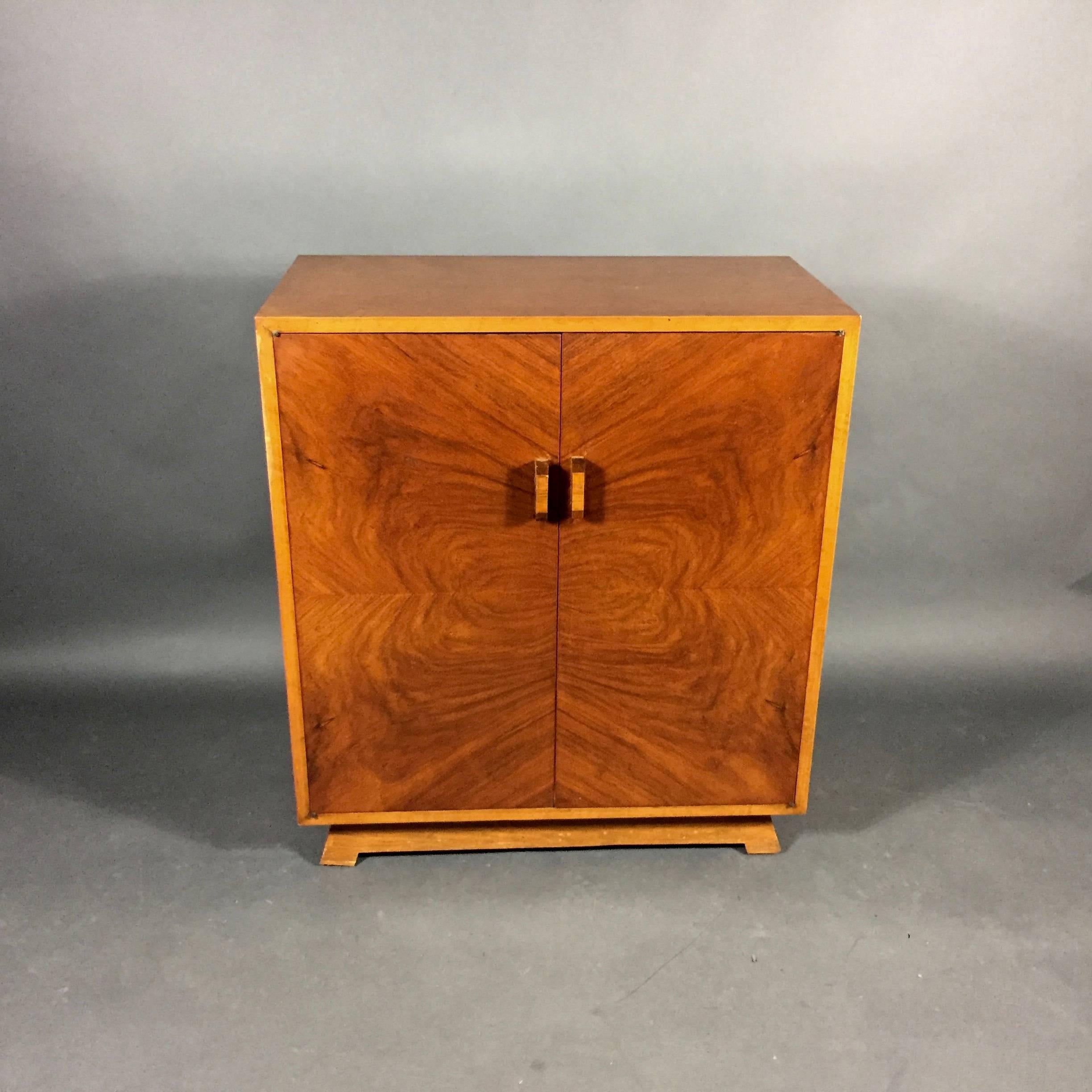 A nicely designed Art Deo period cabinet with quartered burled walnut veneer door fronts from Sweden. Perfectly balanced contrast veneer door pulls and Classic deco angled base. Very sweet touch of brass floral design at four corners of doors at