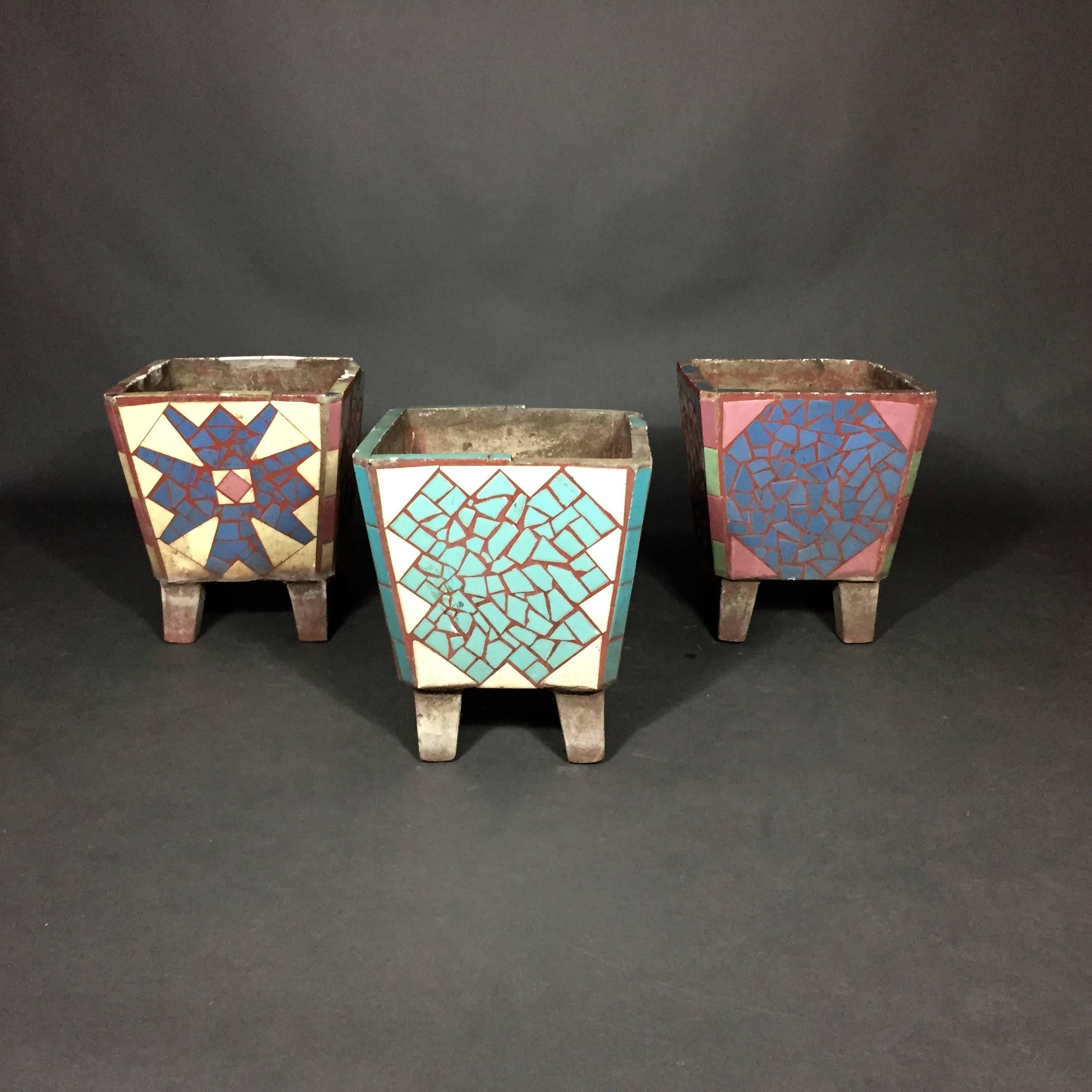 A wonderfully unusual set of garden planters in cast stone, colorful ceramic tile decorated with different designs on each of four planter sides. Supported by four slightly tilted legs. Likely American, 1950s. Some tiles missing at rim - one planter
