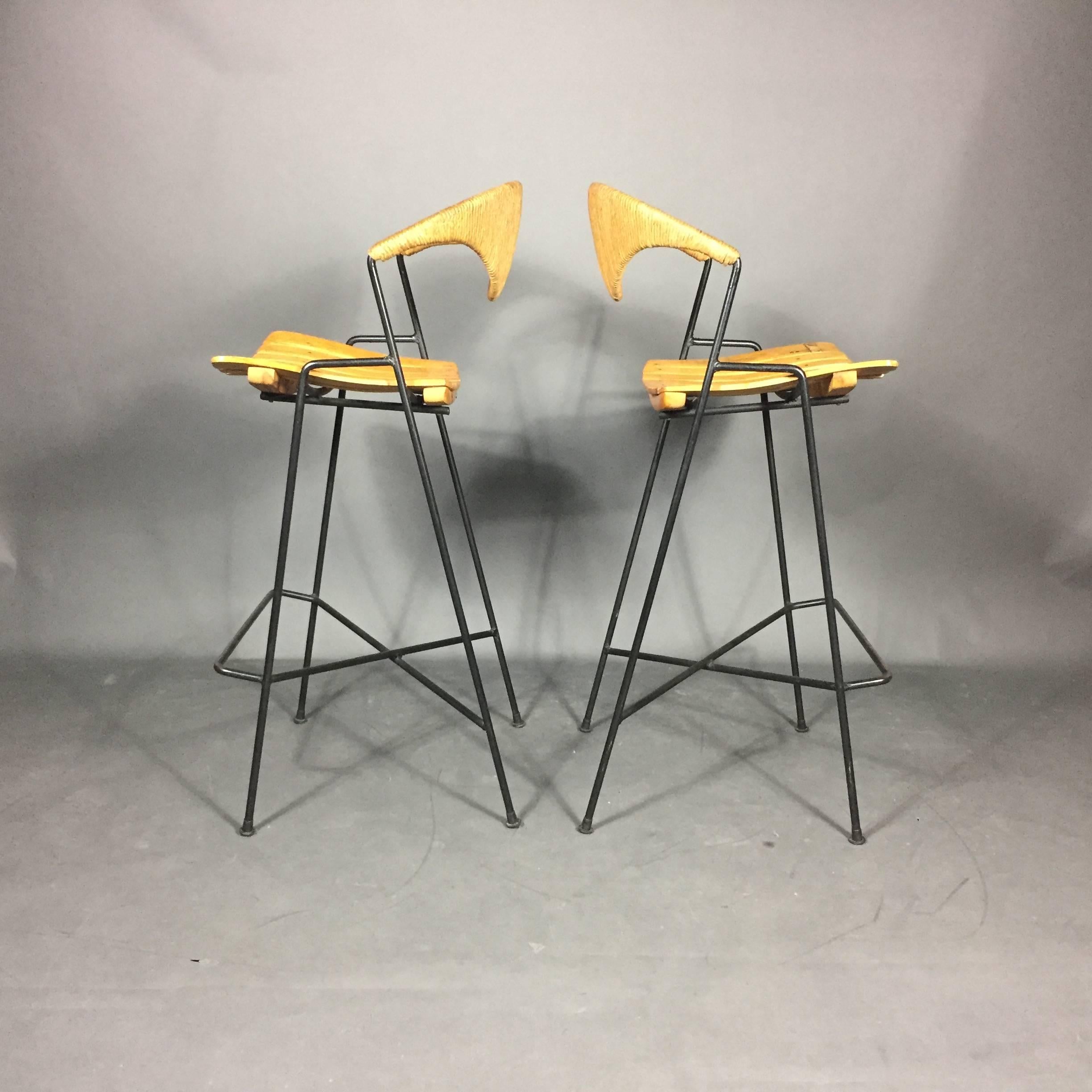 Another Classic American Mid-Century design - the always gorgeous bar stool by Arthur Umanoff for Raymor. All original black lacquered iron frame and intact feet with birch seating and chicly curved backs in rush. Evident repair to one slat of one
