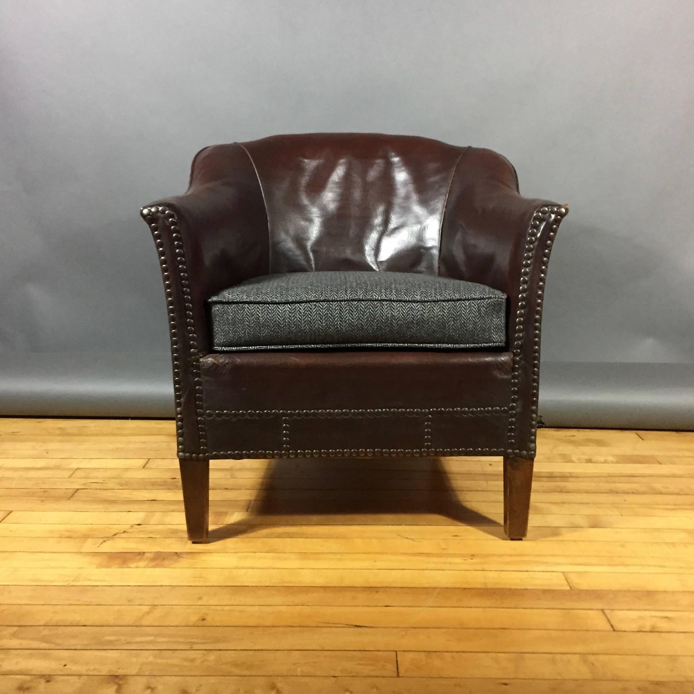 With a bit of Arts & Crafts in outlook, this perfectly sized club chair in luscious dark brown patinated leather with patterned brass tacks. Interesting back shape and newly added seating with Herringbone wool fabric. Great vintage condition,