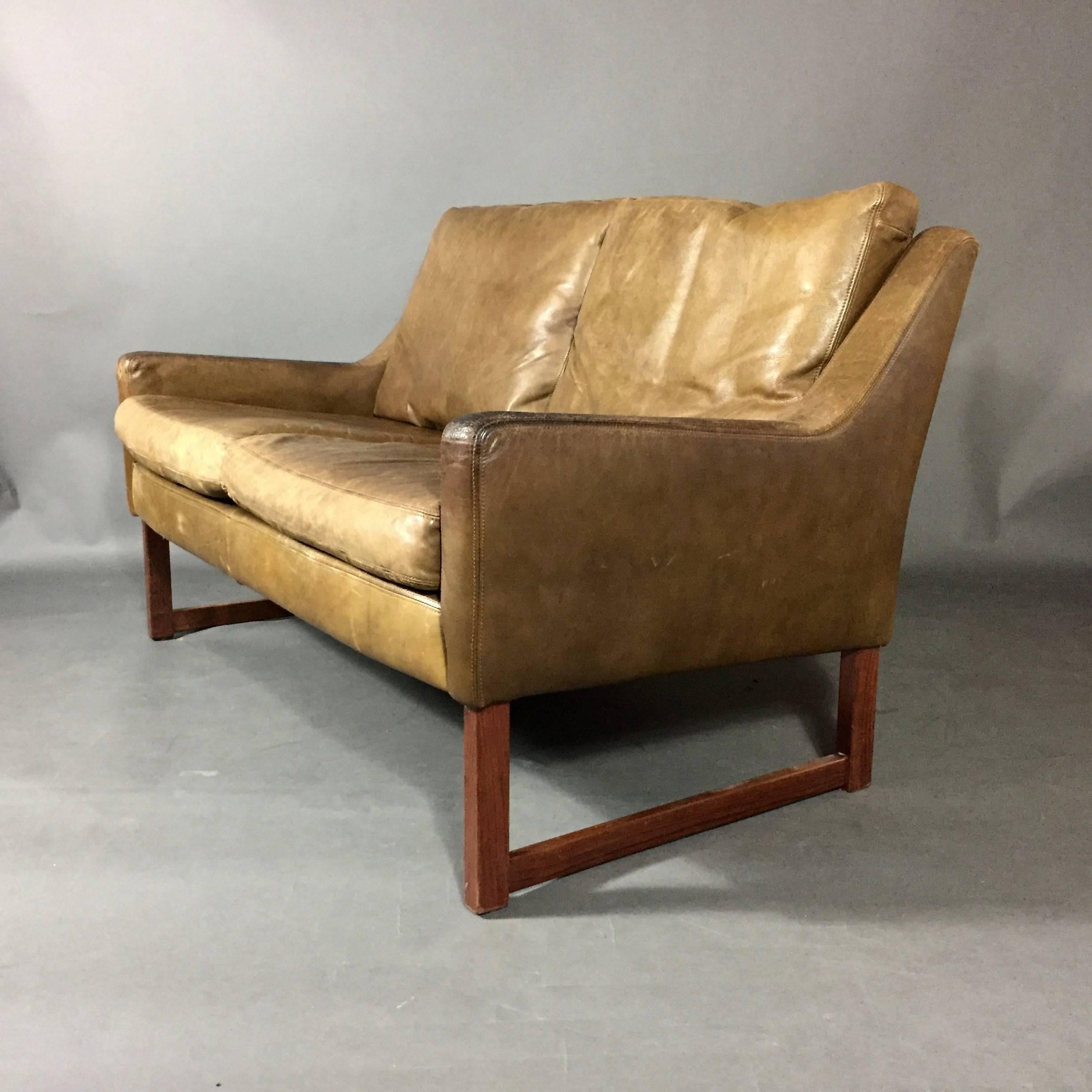 This perfectly sized two-seat sofa is designed with wide leather weave straps on loose cushions and on full back. Cushions are reversible to display smooth brown leather with perfect vintage patina. Square-frame legs provided added stability and a