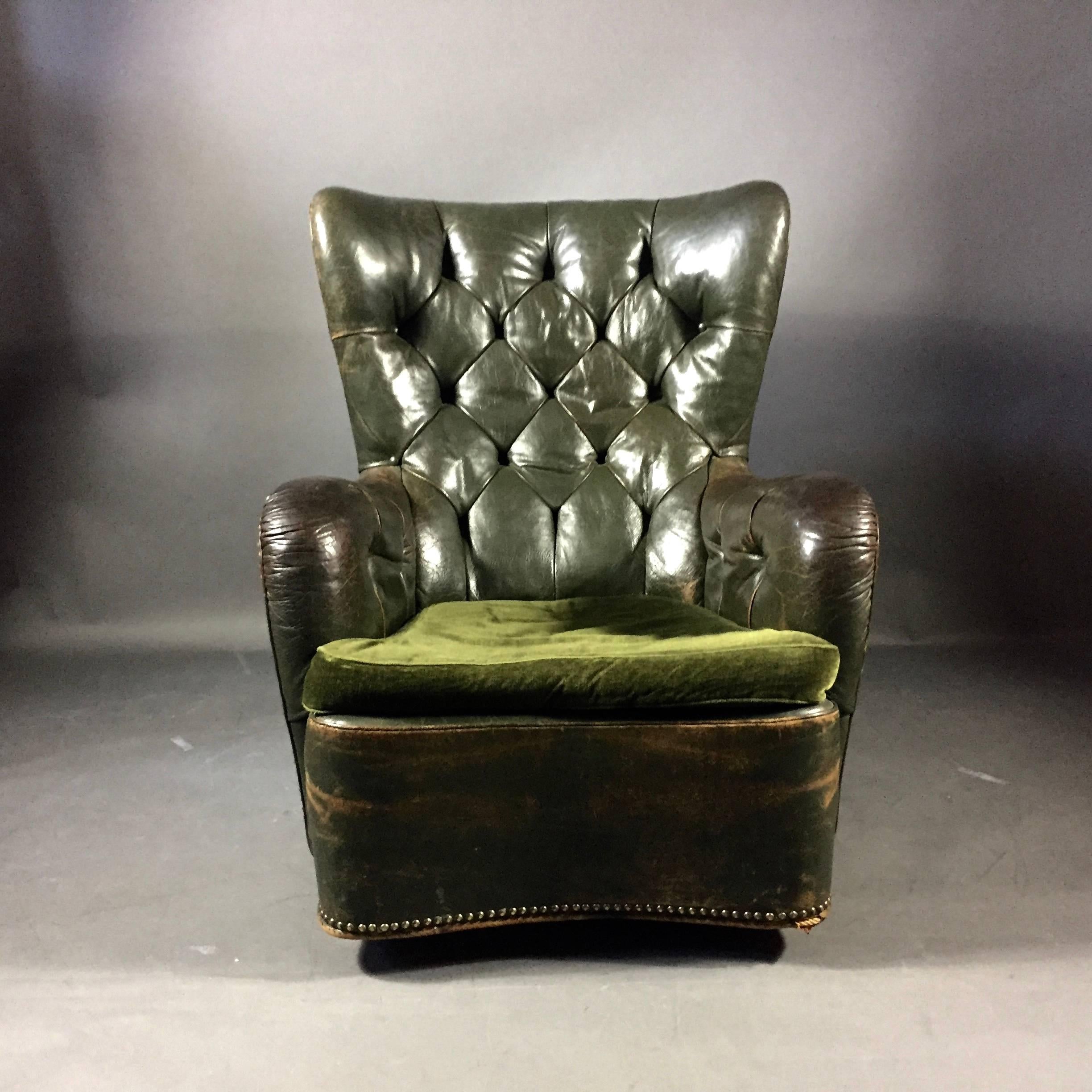 Gorgeous patina on this late Art Deco era 1930s green leather wing chair is perfection with deep tufting on back and arms, curved front and brass tacks overall. Non-original green velvet loose cushion. In terrific vintage condition. Danish design.