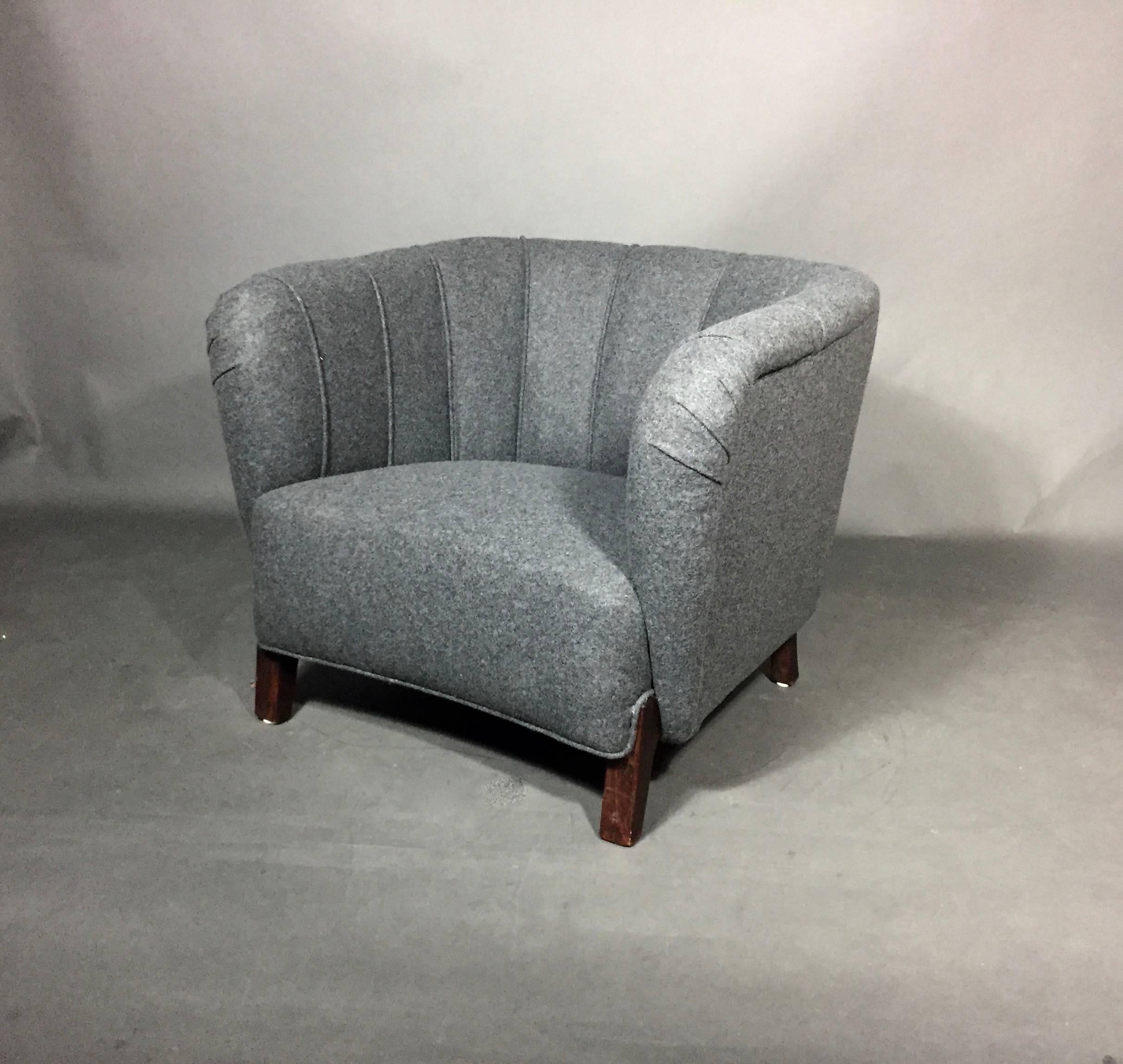 An unusual frame form on this 1940s Danish oversize club or lounge chair. Over padded angled front legs with curved front panel. Deep seat with nicely proportioned welting covering the curved back. New grey Kavadrat felted wool upholstery. Solid and