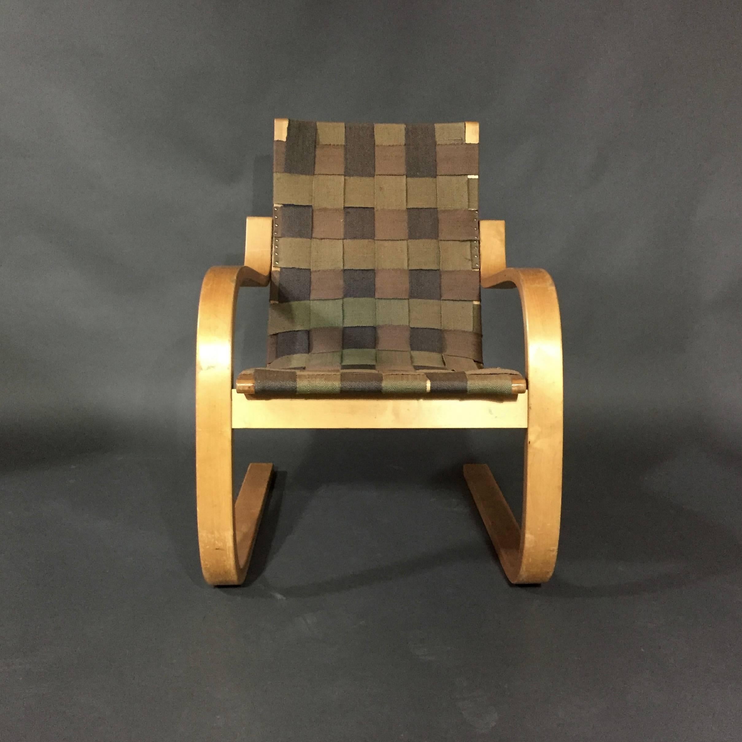 Early Alvar Aalto cantilever armchair, model 406. The laminated birch plywood frame originally came with a woven cane webbing, replaced with an naturalistic alternating-color cotton webbing some time ago as it has terrific patina and coloration.