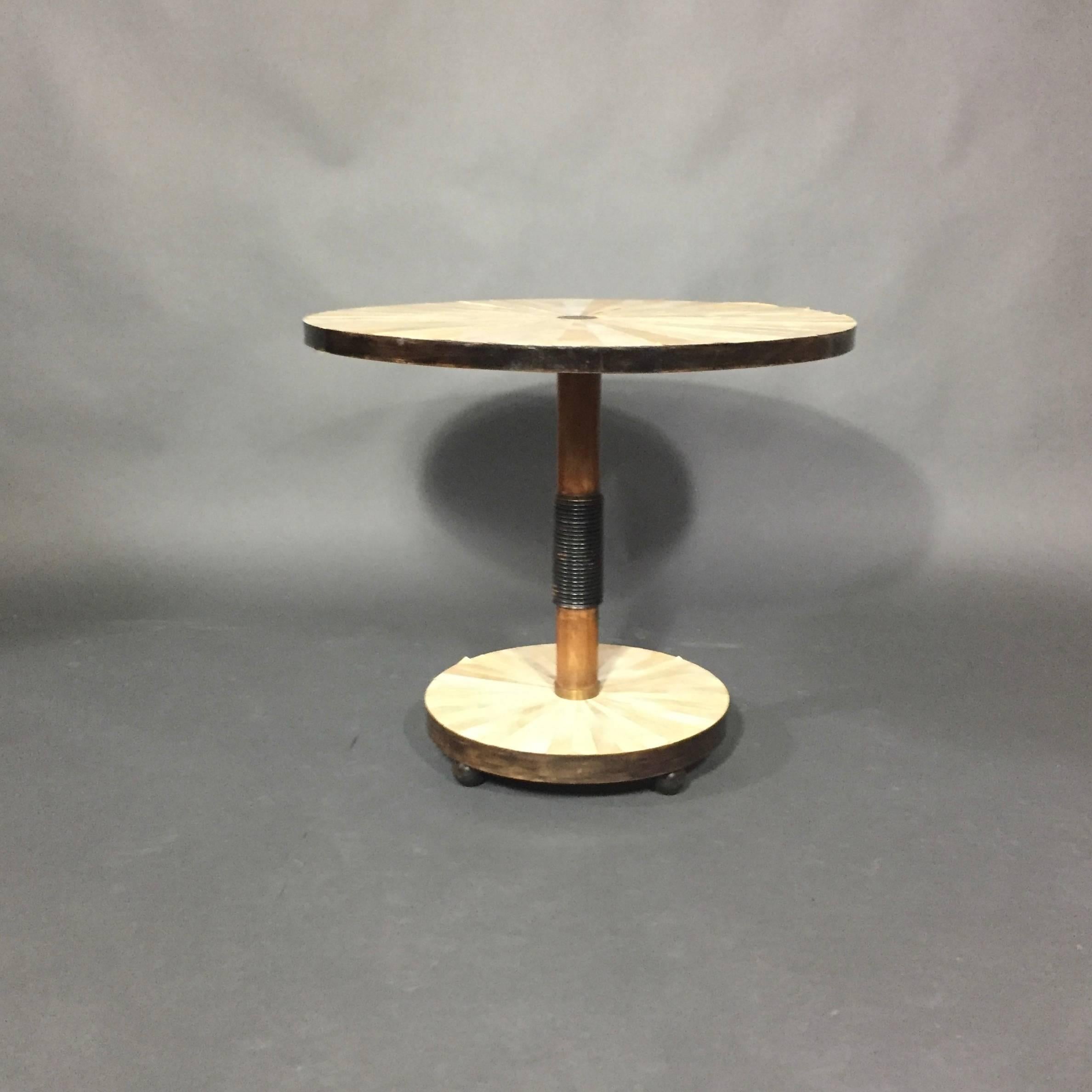 An unusual design from the late 1930s with applied parchment to top and base in a striking radiating pattern.  Center post with black-painted carved wood and brass accents at top and base.  On three-ball feet.  Probably Continental.