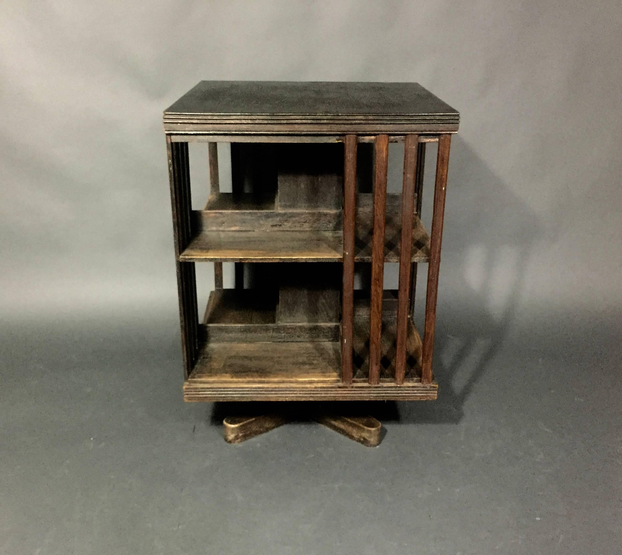 An unusual and perfectly vintage revolving bookcase in oakwood with four sides and two shelves. Vertical slats play homage to the Arts & Crafts movement. England, circa 1930. Wear and marks to finish overall.