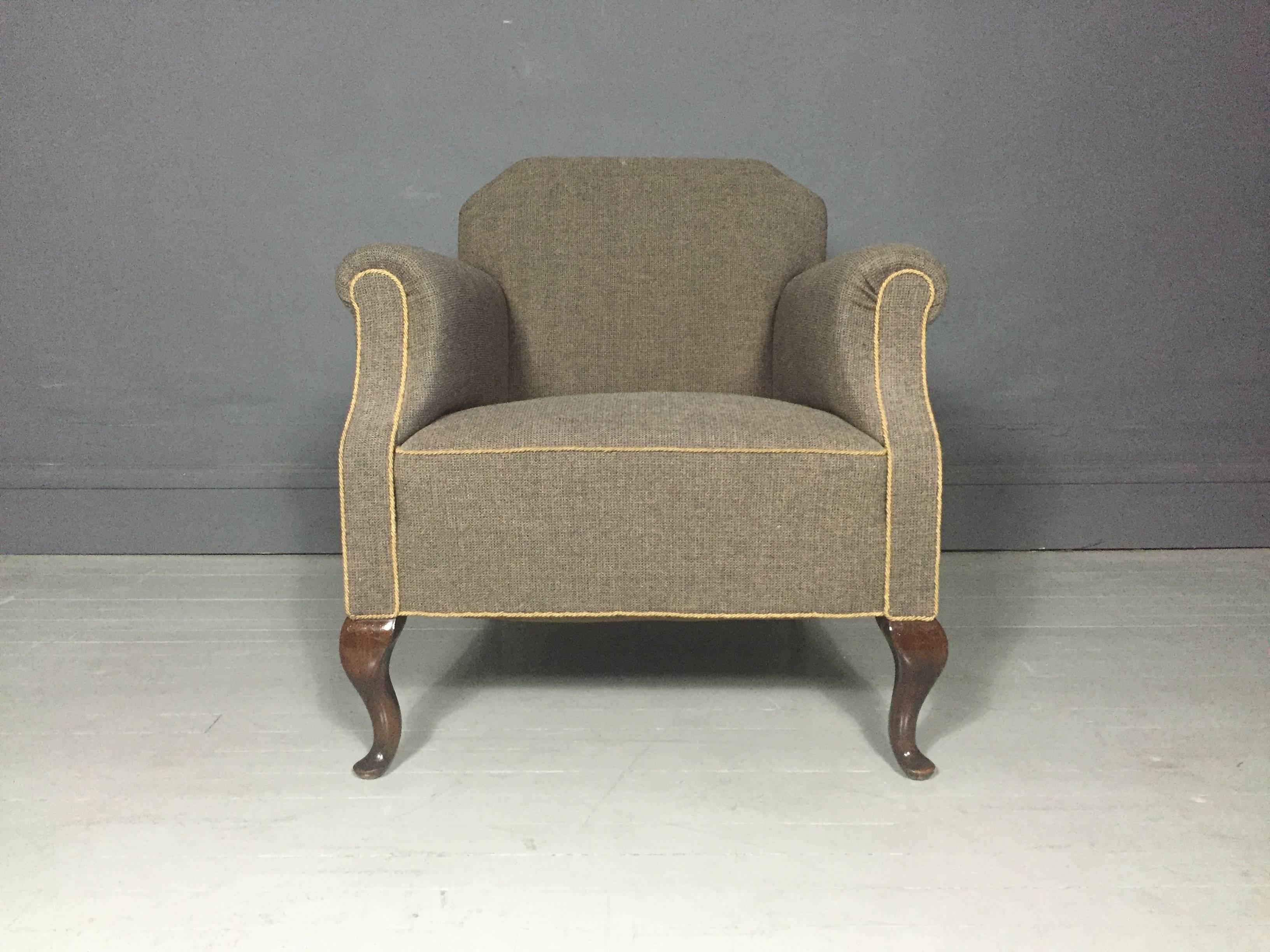 A beautifully proportioned library or armchair with newer brown tweed wool upholstery and contrasting trim, front legs in the Queen Anne foot pad or cabriole style, 1940s, likely English. Excellent condition.