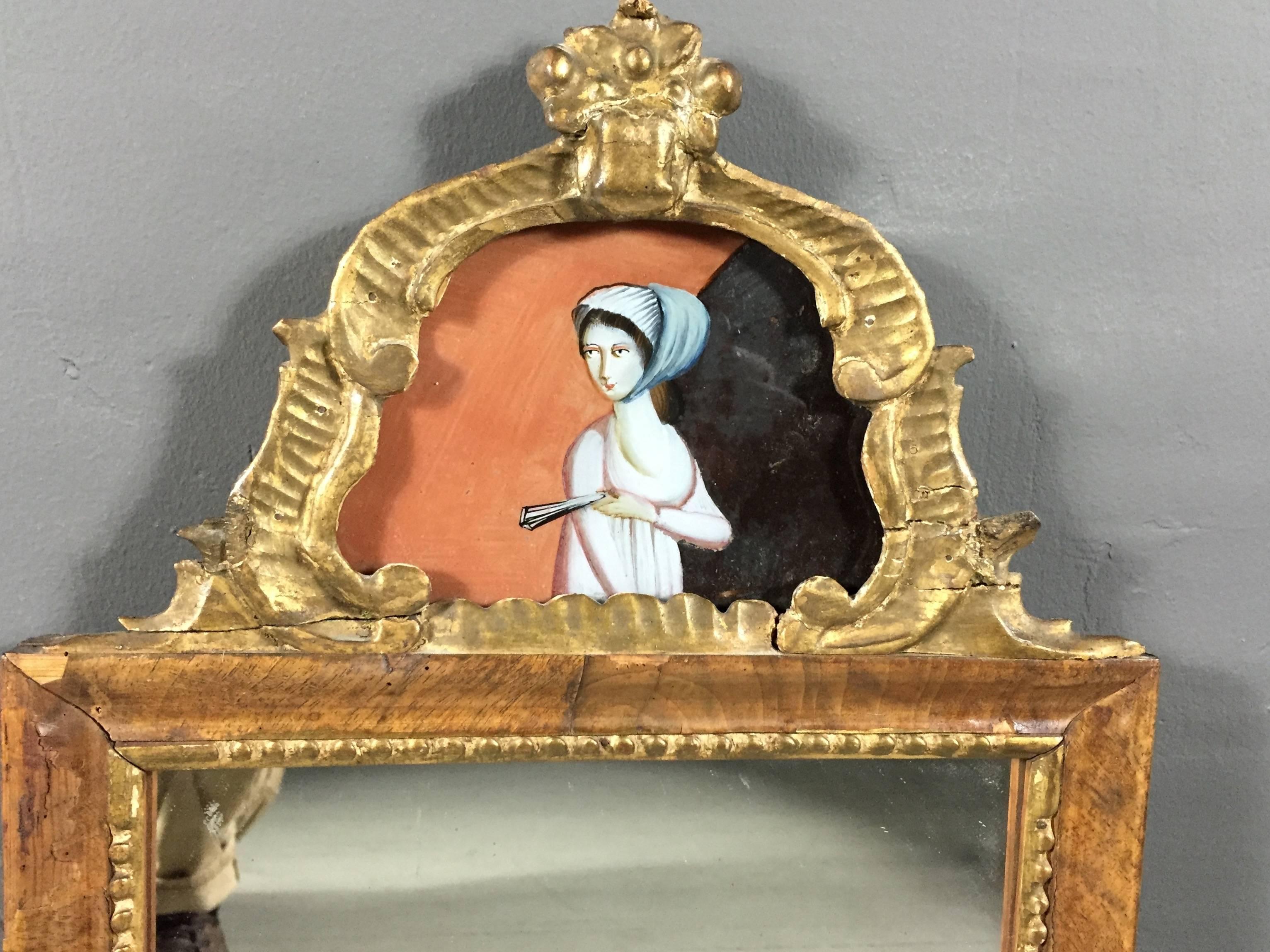 A very wonderful and unusual late 18th century walnut veneer mirror trimmed in gilt beading, with a later added Rococo style pediment that includes a beautiful reverse glass painted portrait, top-most portion of a flower basket is papier-mâché.