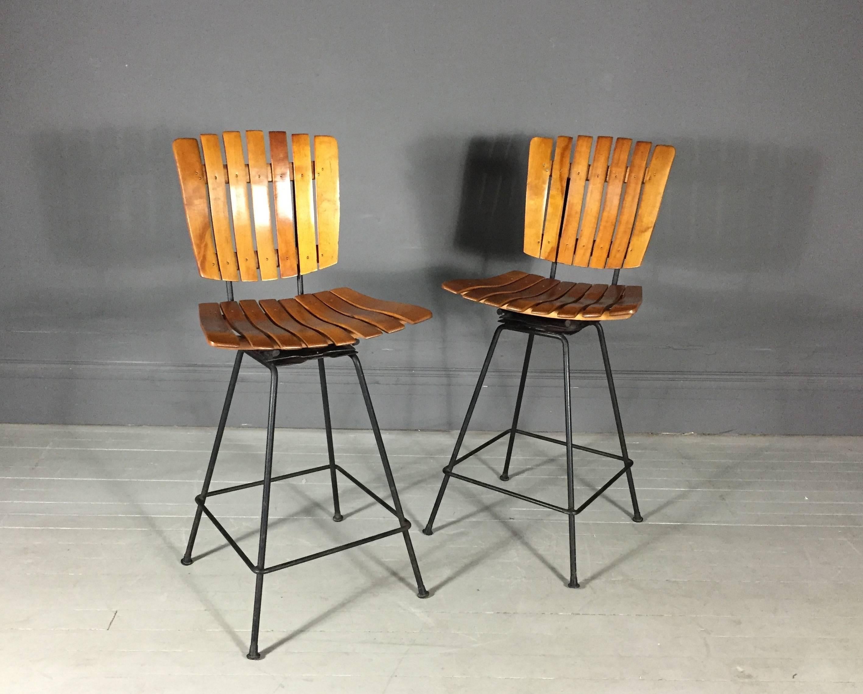 A very good pair of counter height swivel bar stools in honey-colored slatted birch, iron frames and all original feet, Arthur Umanoff, USA, 1950s.

Great vintage condition.