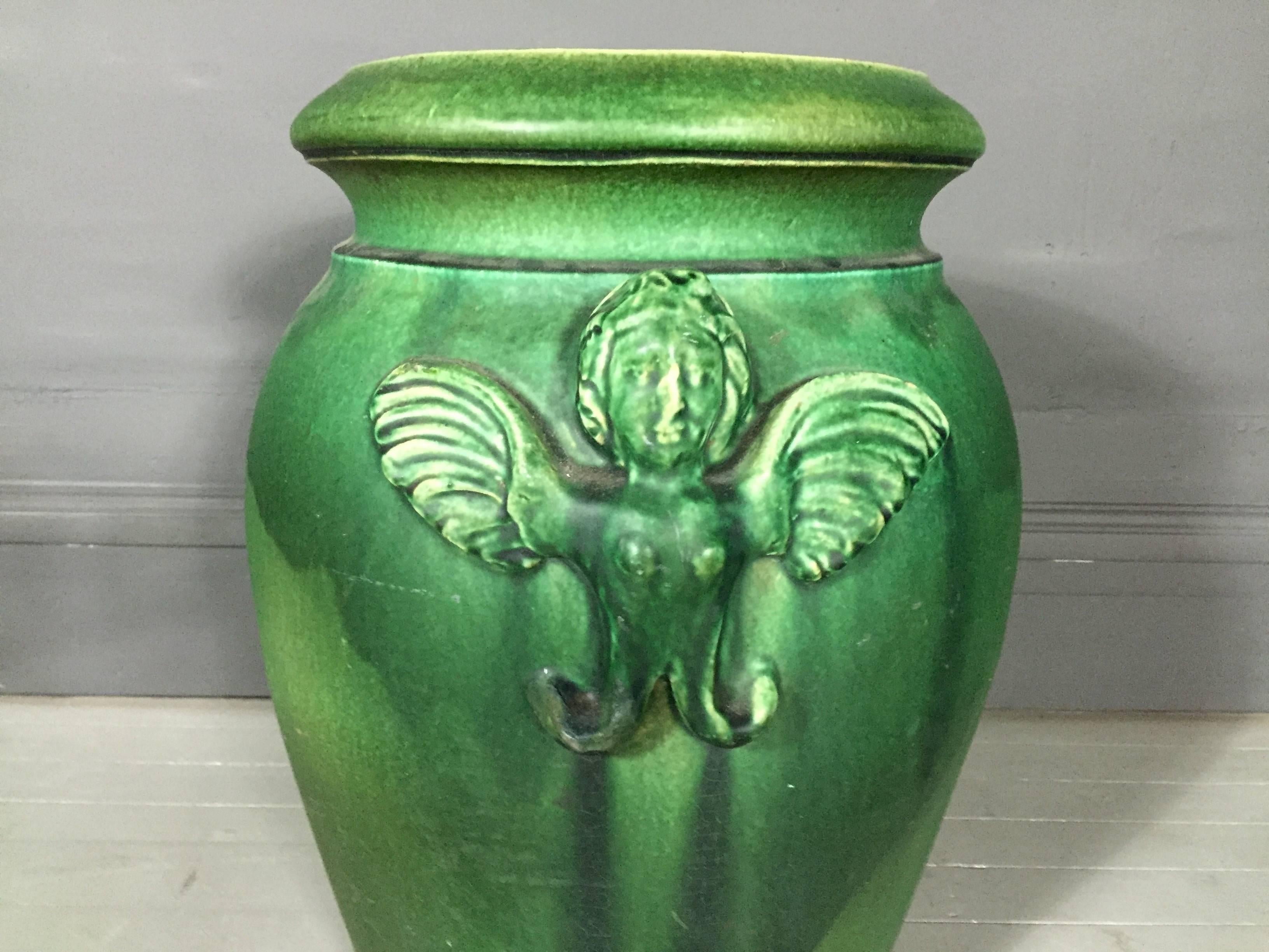 An unusually large arts and crafts oil jar with a pair of relief angels, mixed green glaze on stoneware, 21