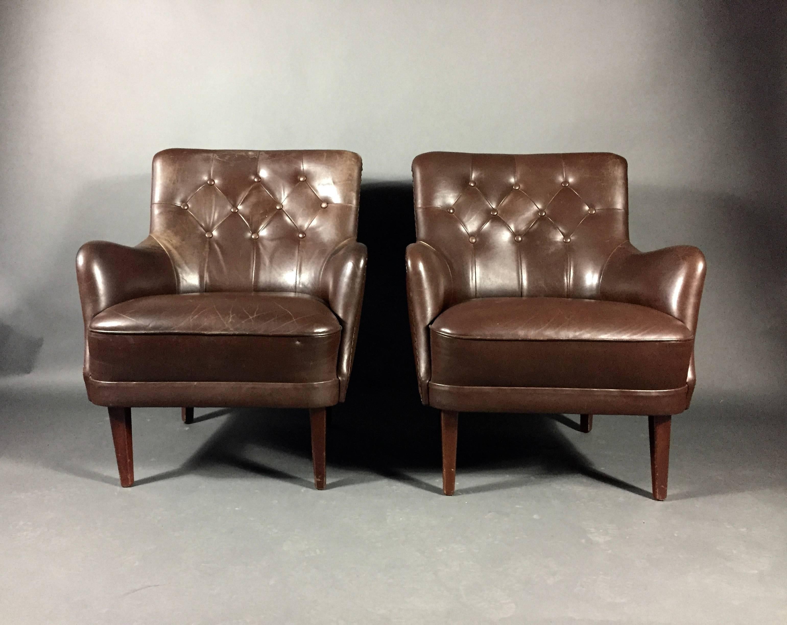 A perfect pair of armchairs upholstered in brown buttoned leather, tapered legs in stained beech by Danish furniture designer in the 1950s. Minor wear to leather very nice condition.