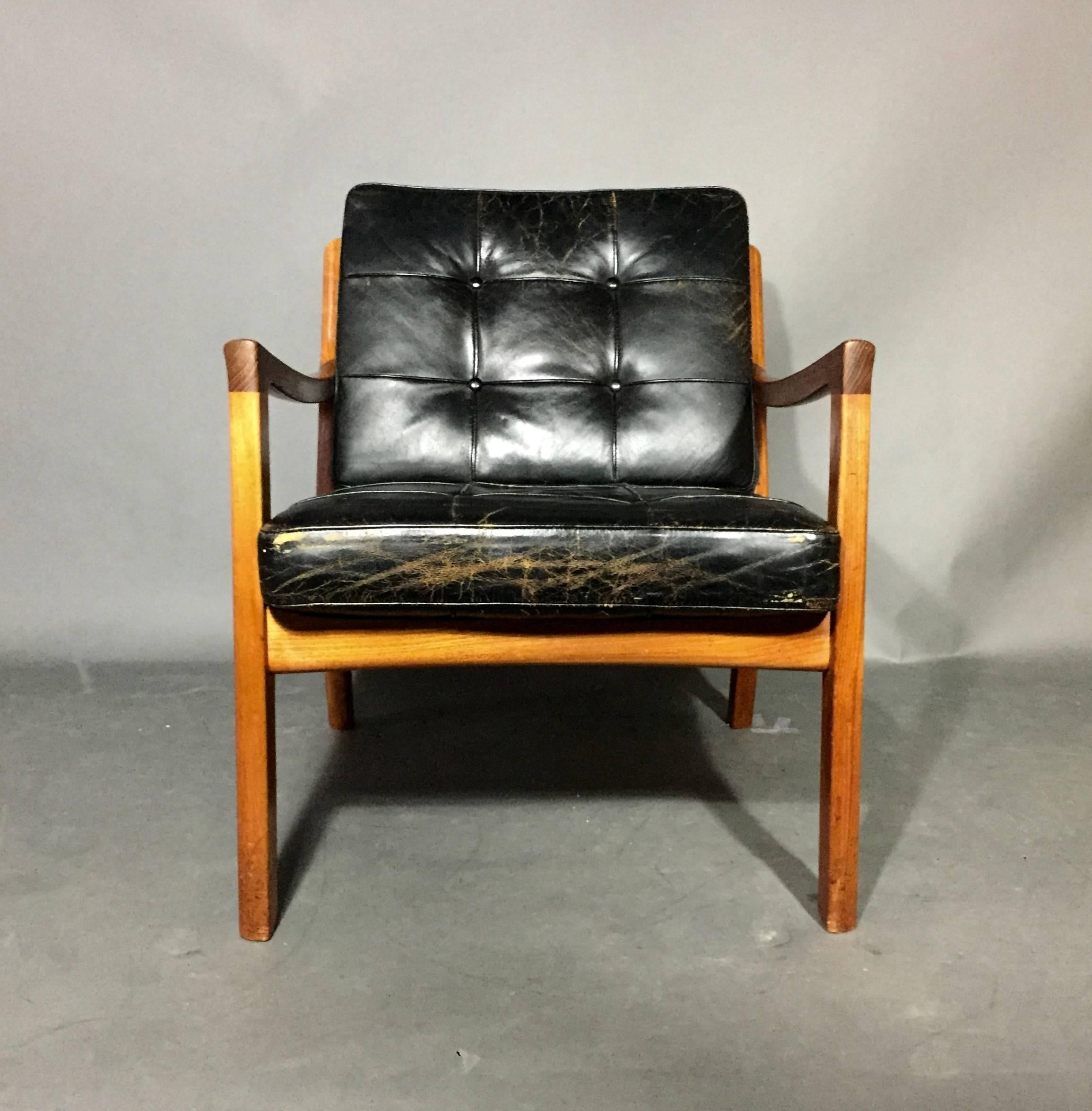 A Classic in Mid-Century design, this Ole Wanscher design is more generous than usual Scandinavian pieces of the era. Teak frames and buttoned loose cushions in black leather, wonderful patina, Denmark, 1950s. Marked France & Son. Missing buttons to