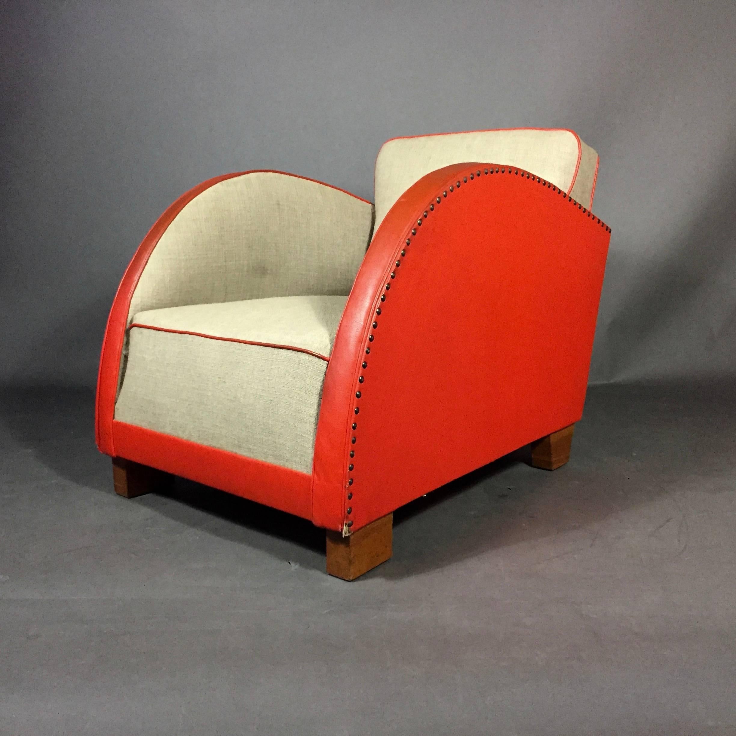 Spectacular is the visual sweep of arm on this diminutive club chair with original and early usage of Naugahyde - a prefect and vibrant red/orange. Wide woven weed wool fabric to seating with contrast red piping and brass tacks to sides. Very solid