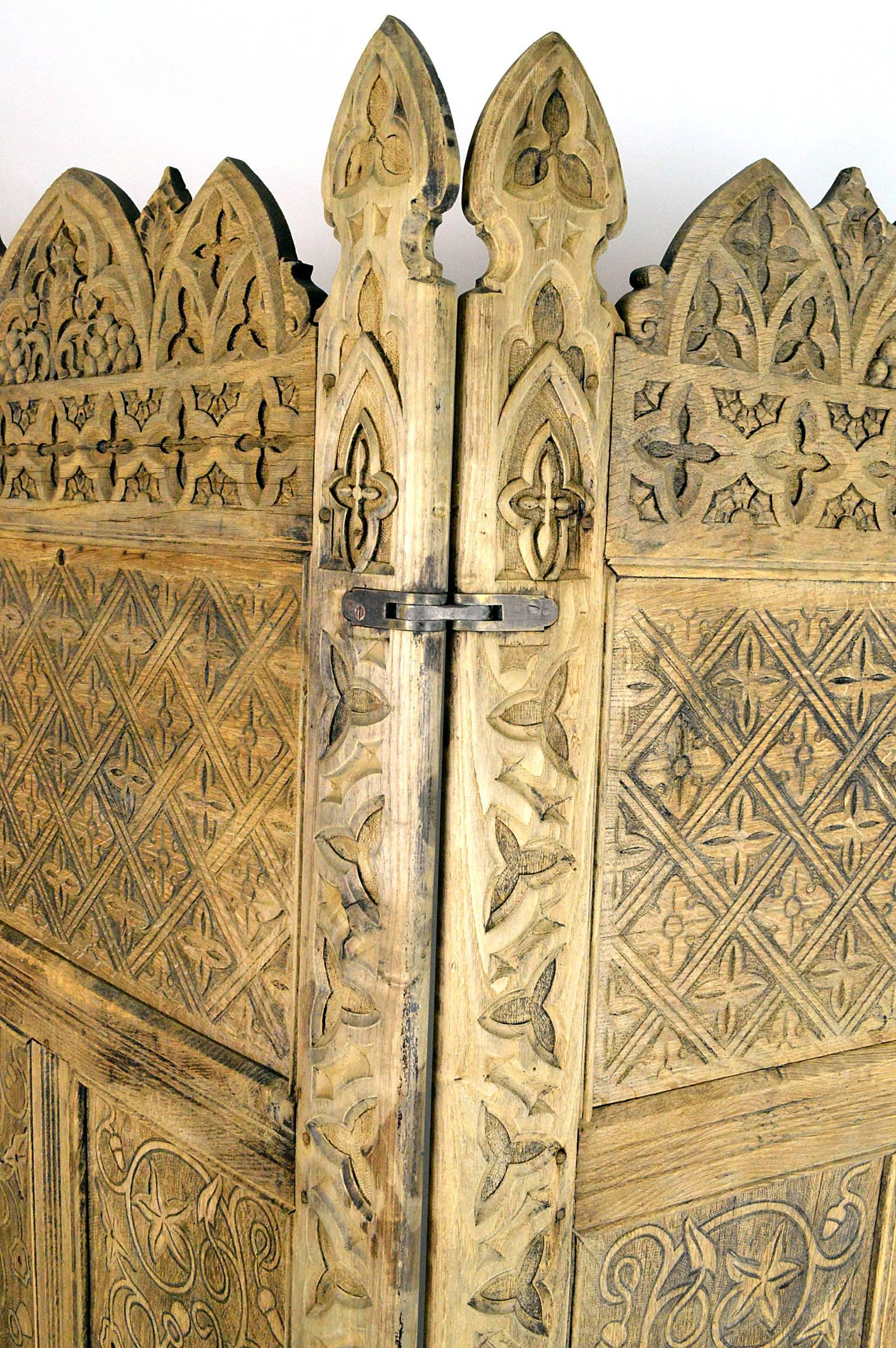 Three-panel English oak Gothic Revival screen having carving throughout with a bleached wood finish.