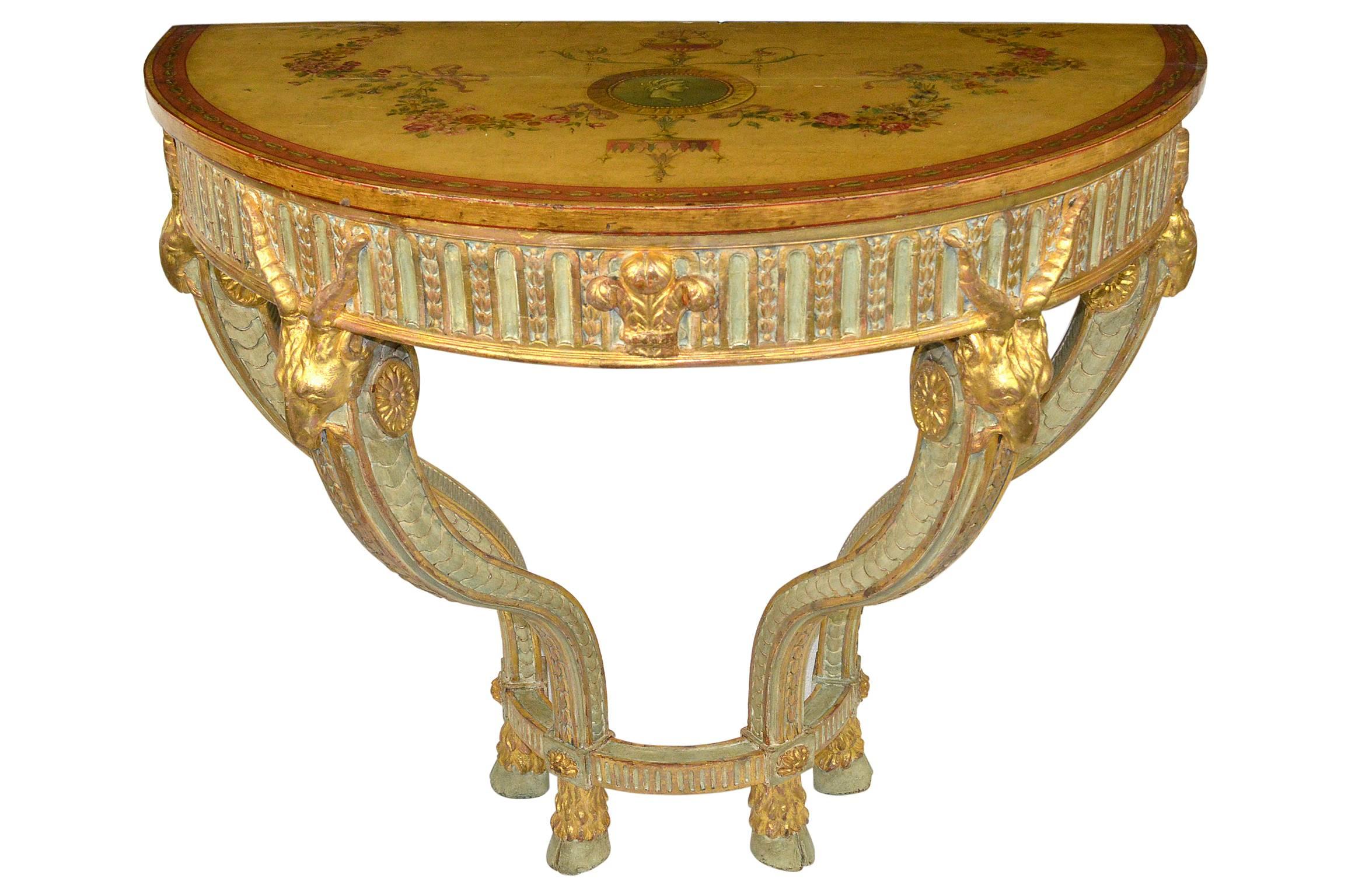 A fine pair of 19th century George III style console tables. Top having hand-painted decoration of swags of flowers and a medallion center. The skirt having paint and gold gilt decoration. Raised on hoofed feet, and having gold gilt ram’s heads at