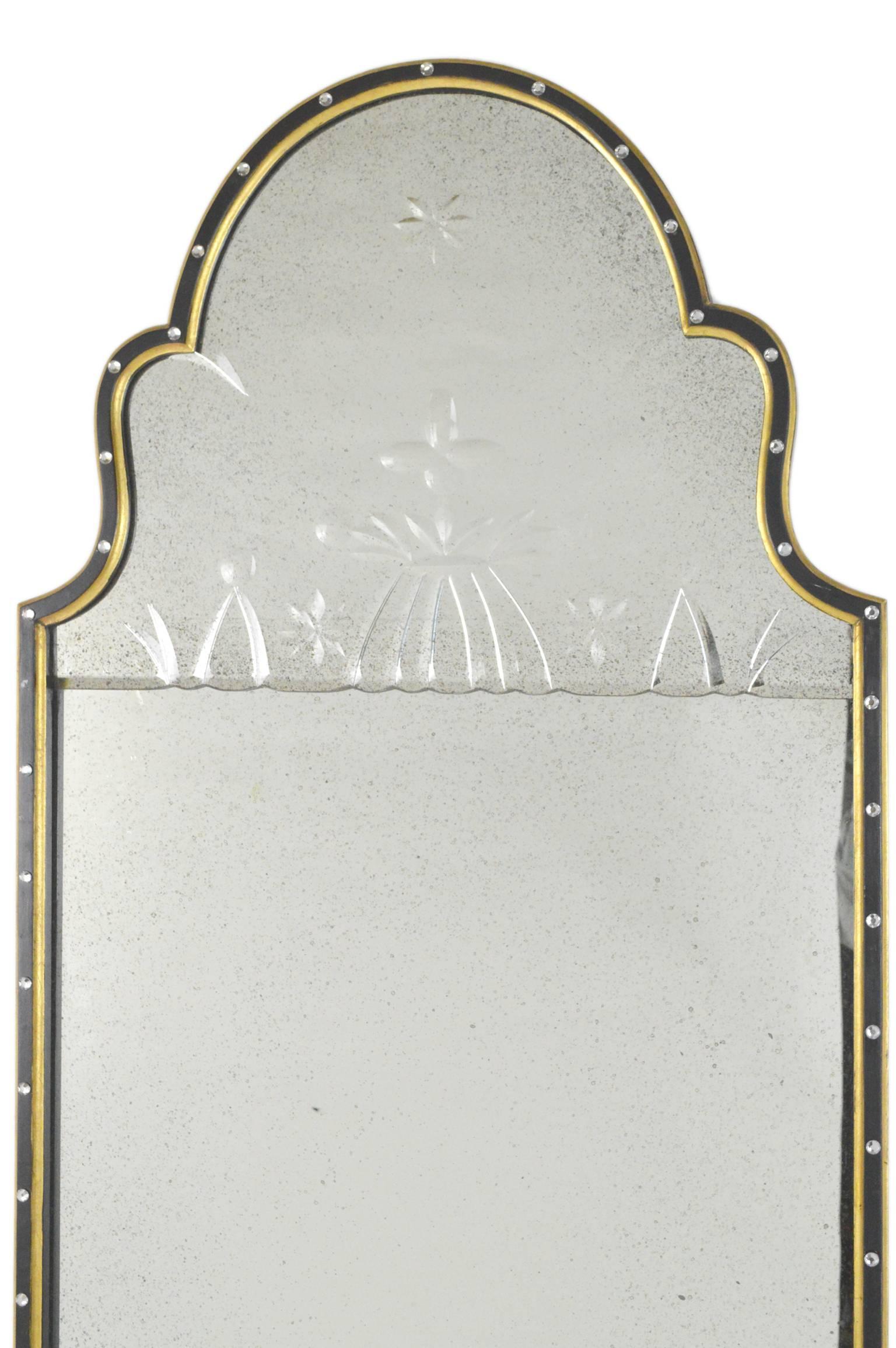 Art Deco style Venetian mirror having cut decoration to upper plate in ebonized and gilt frame decorated with faceted crystals.