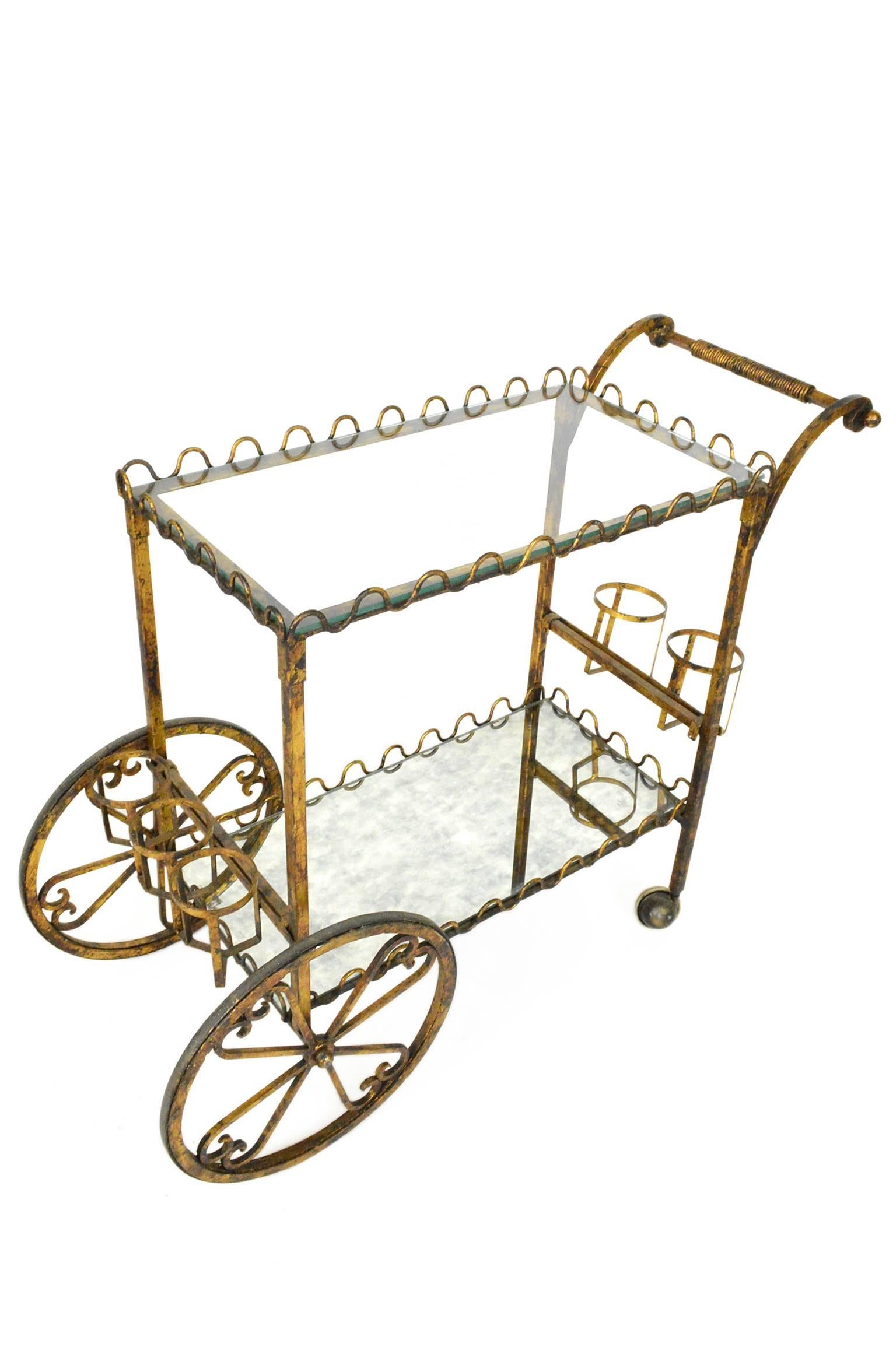 Mid-Century gilt iron bar cart or tea cart, having a great form with loop decoration at its top and bottom; maintaining original patina throughout.