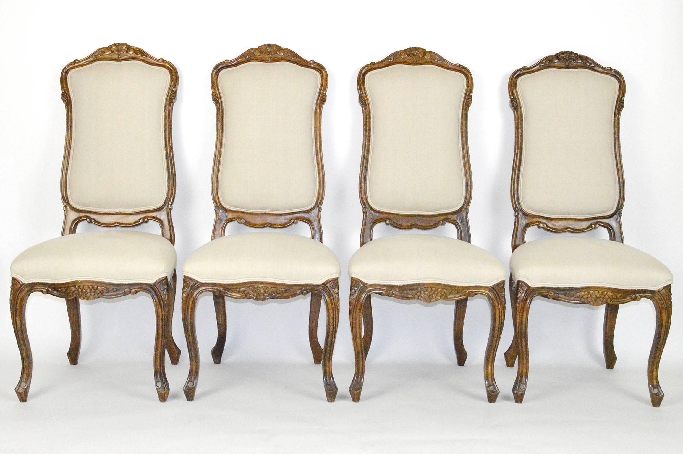 Set of four Louis XVI style fruitwood high back side chairs covered in linen.