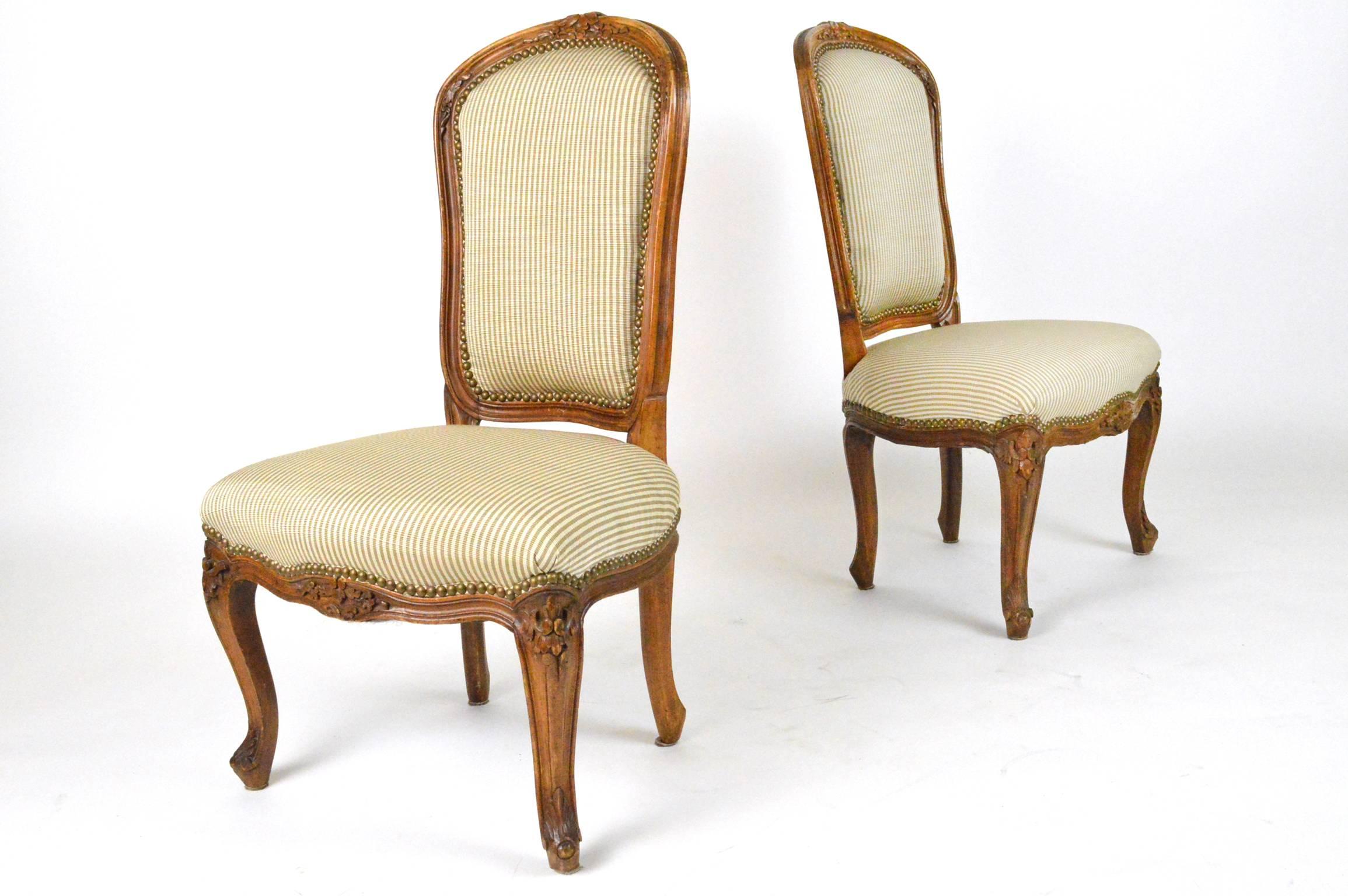 Pair of Louis XV style fruitwood slipper chairs covered in a neutral beige stripe upholstery with nailhead trim.