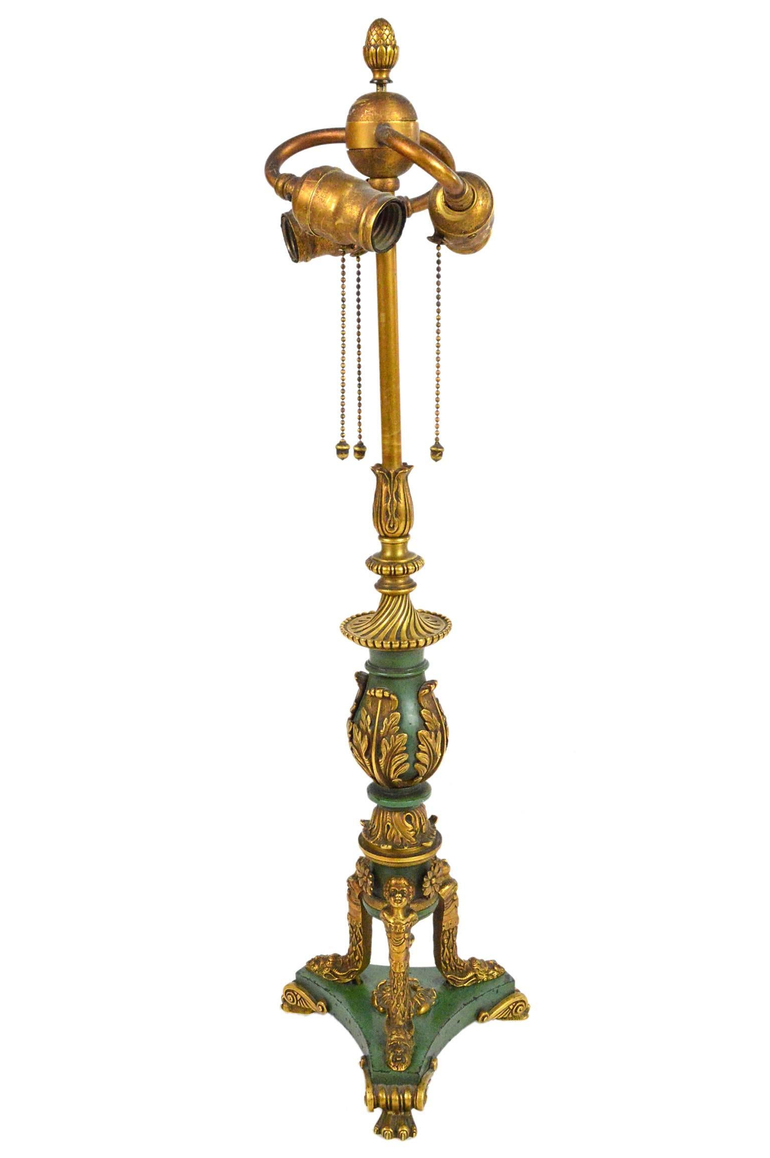 Empire style gilt bronze and painted table lamp having center decorated acanthus leaves, three hubbell sockets, tripartite base with cherub heads and bacchus masks; ending in paw feet. Attributed to E.F. Caldwell, NY.

