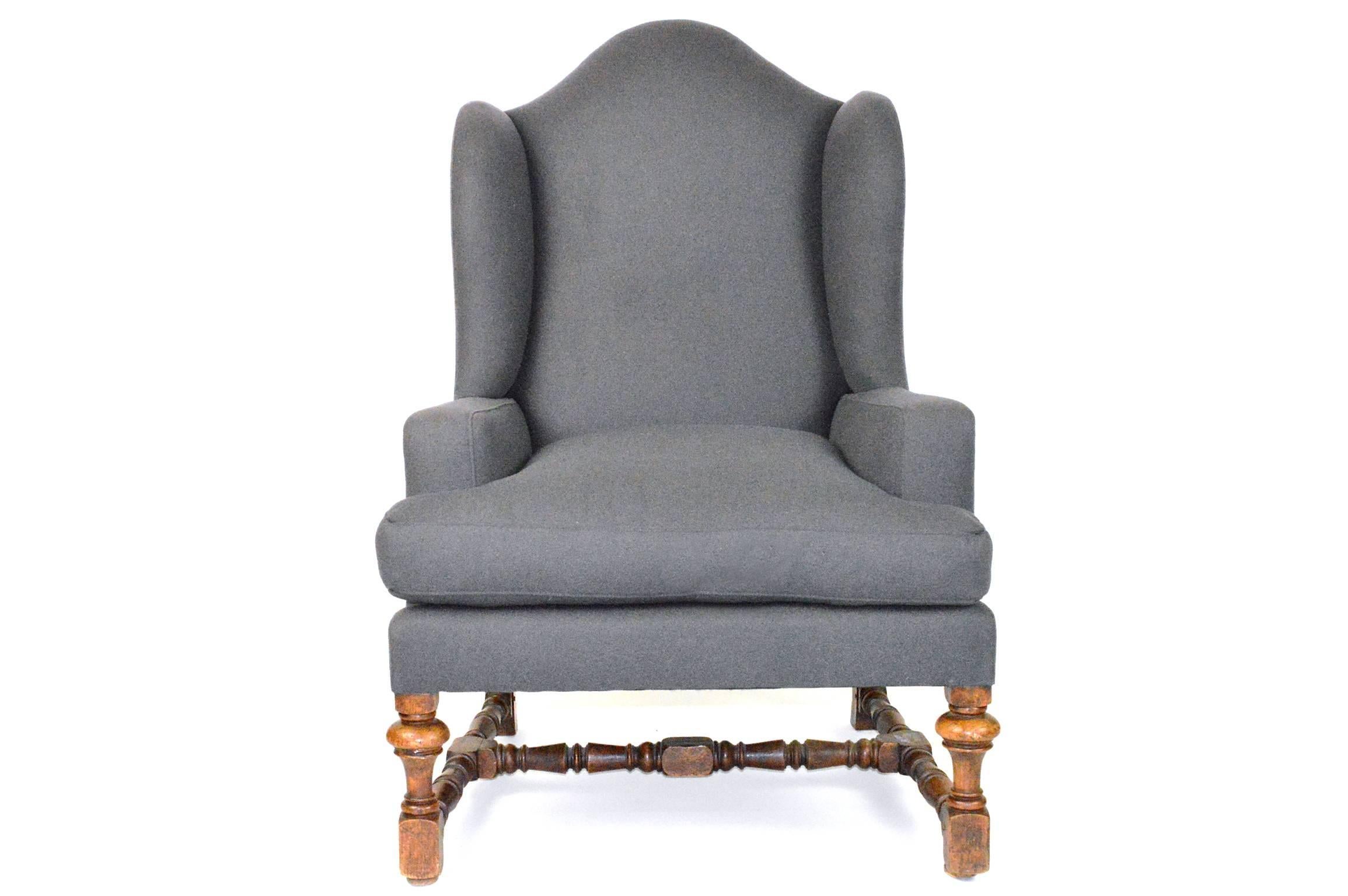 19th Century Baroque style wingback chair having an arched crest over two wings, upswept arms, removable cushioned seat surmounting oak ring block and baluster turned legs and stretcher. Upholstered in a grey felt wool.