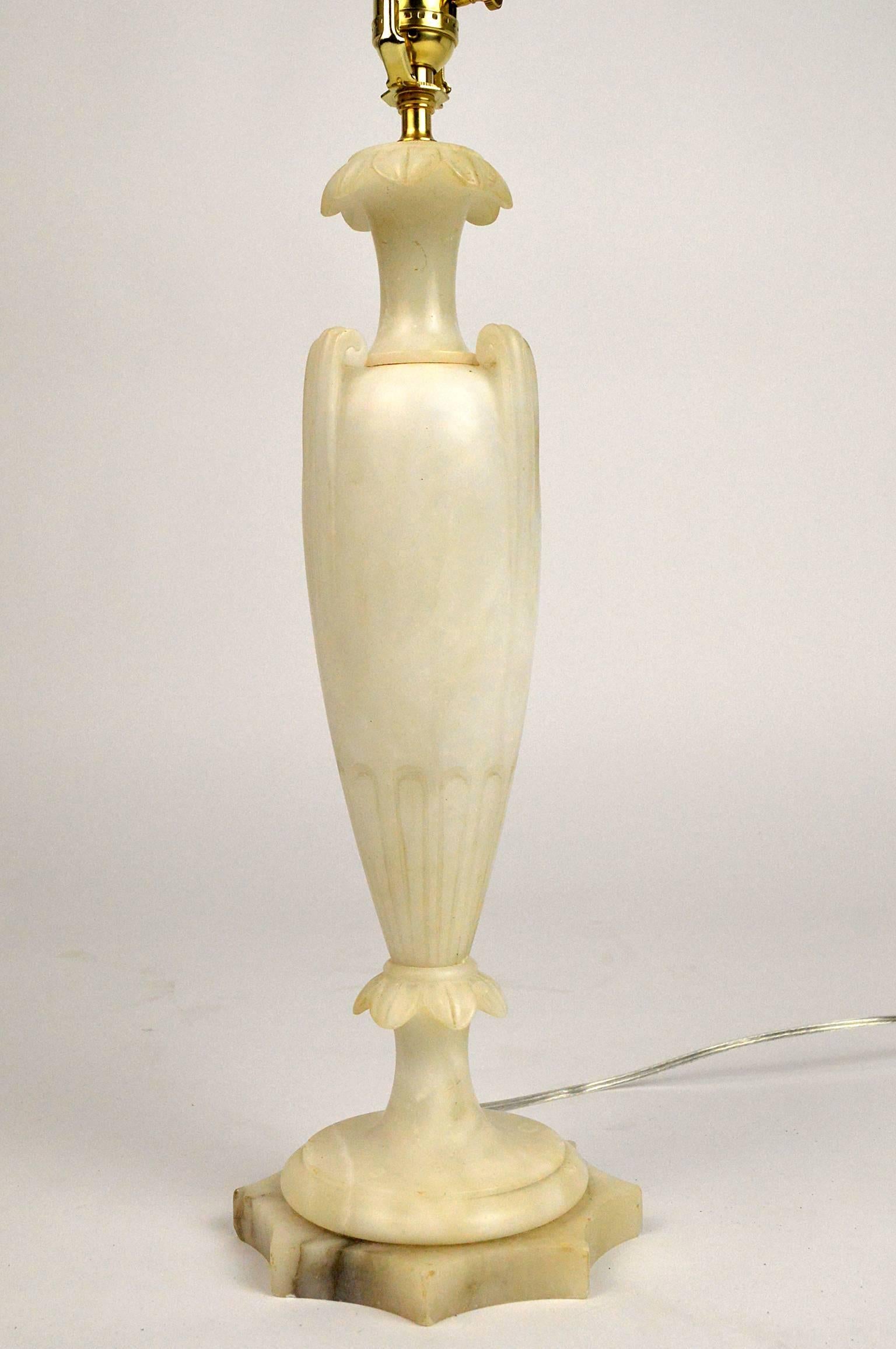 Neoclassical style Italian alabaster lamp with an slender urn form and leaf Silhouette. Overall ivory color and gray veining resting on a rounded star base.
Measures: 25.5