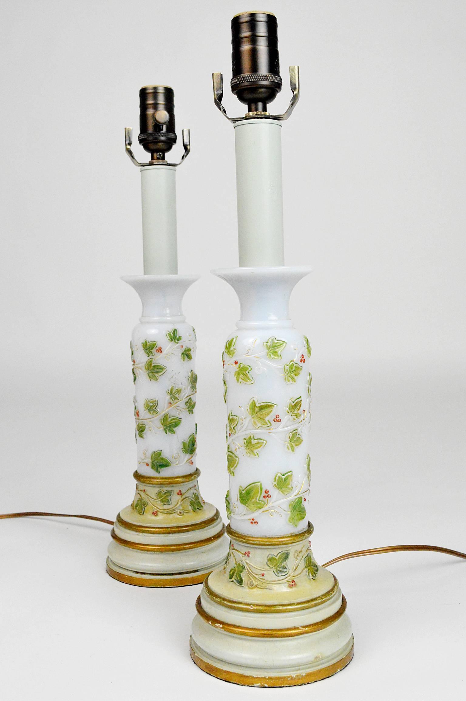 Pair of French opaline glass table lamps with hand-painted and gilt foliage, raised on turned wood bases.