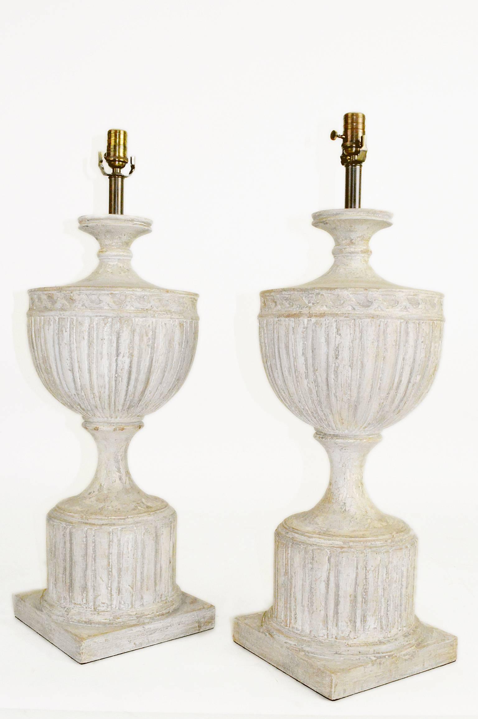 Pair of large neoclassical style urn form, carved wood table lamps with a custom distressed painted finish. 32.5