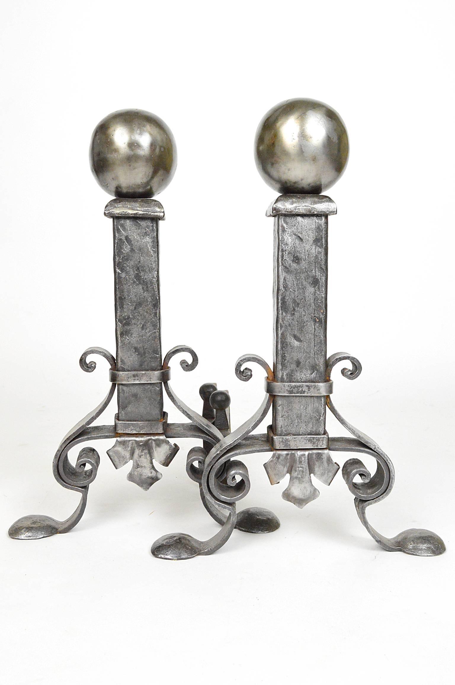 Pair of hammered polished steel andirons ending in padded feet.