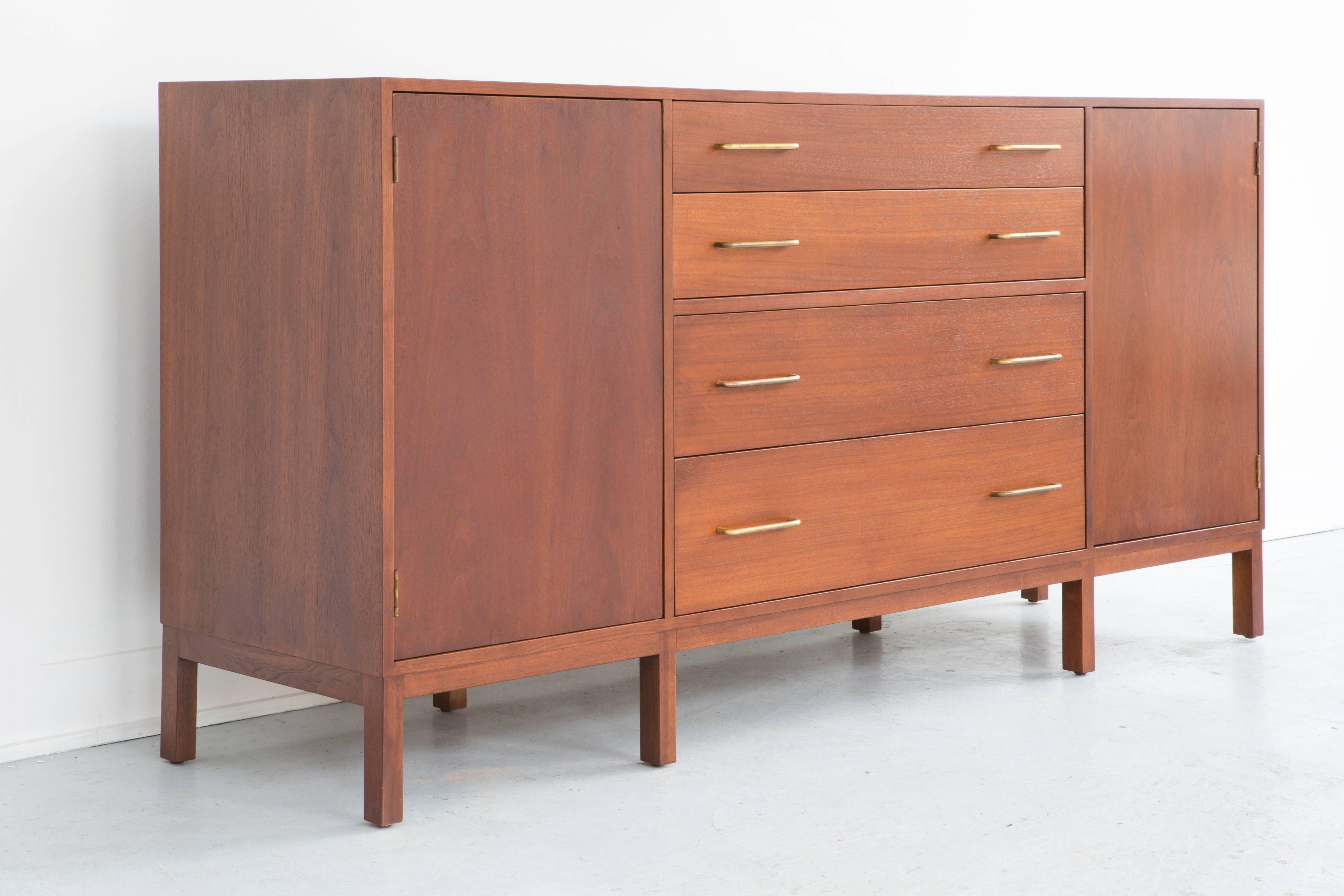 Edward Wormley for Dunbar sideboard. Walnut with brass pulls. This rare piece is in impeccable original condition. Four center drawers with gullwing style doors on either side. Mid-Century utility at its finest.