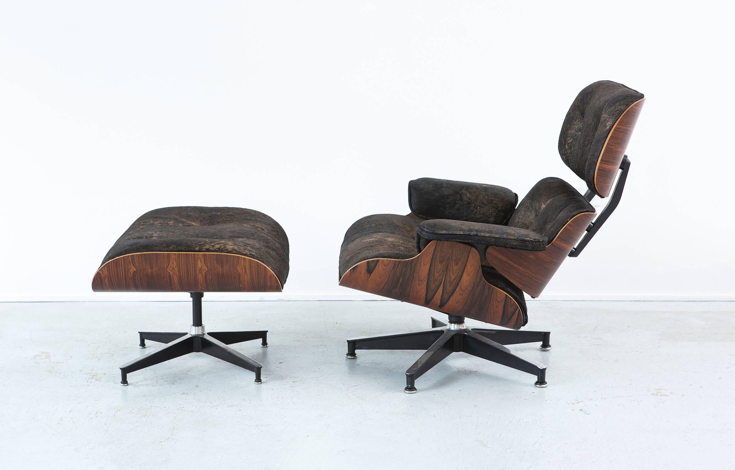 Eames 670 lounge chair and 671 ottoman. 

Designed by Charles and Ray Eames for Herman Miller, 

USA, d 1956 / circa 1978.

Reupholstered in acid washed black and gold cowhide with rosewood shell refinished.

Measures: 33