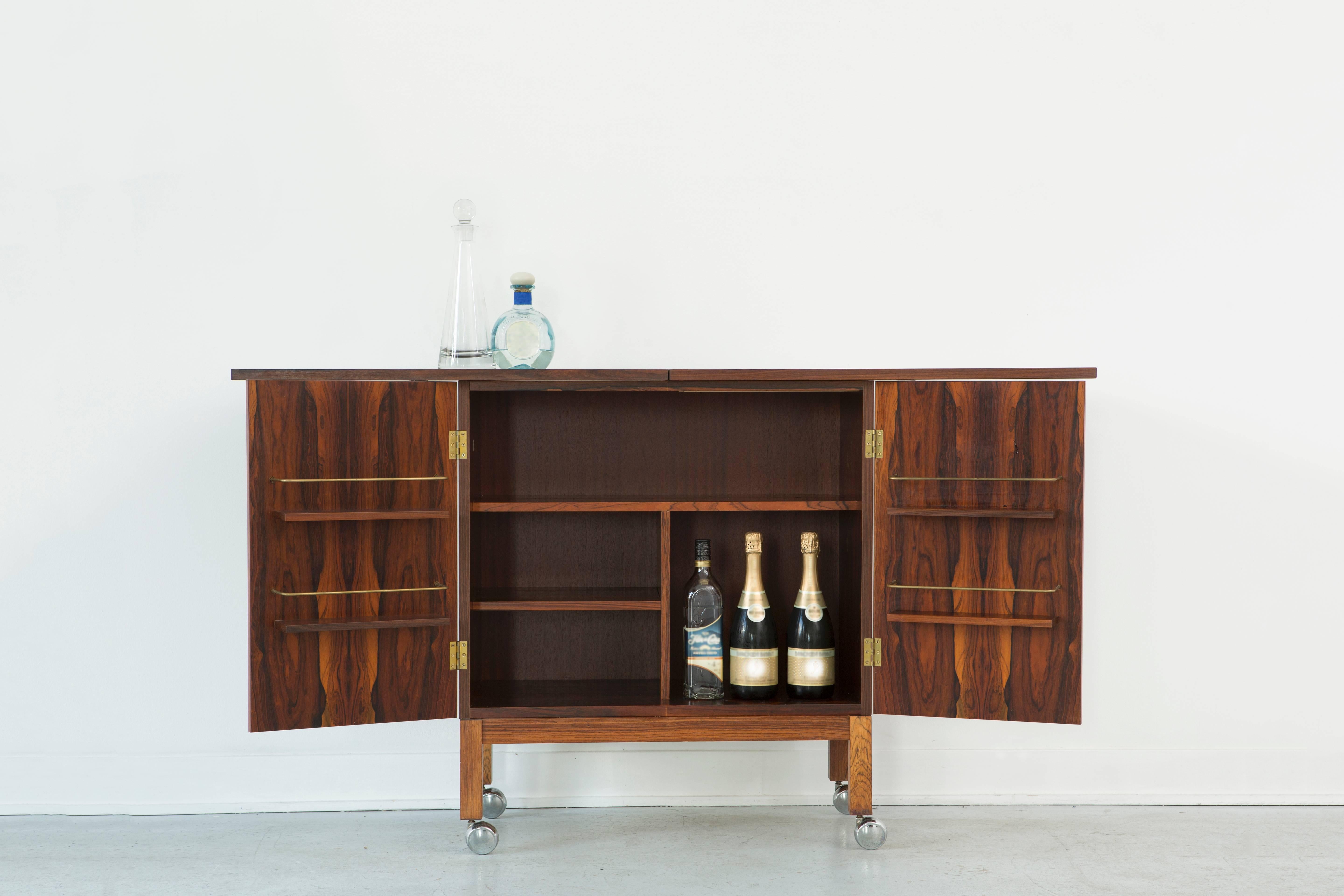 Flip top dry bar designed by Torbjørn Adfal for Bruskbo

Norway, circa 1960s.

Rosewood

This dry bar on rolling casters is lockable with a variety of options for storing your alcohol and glassware 

Torbjørn Afdal is considered one of Norway's most