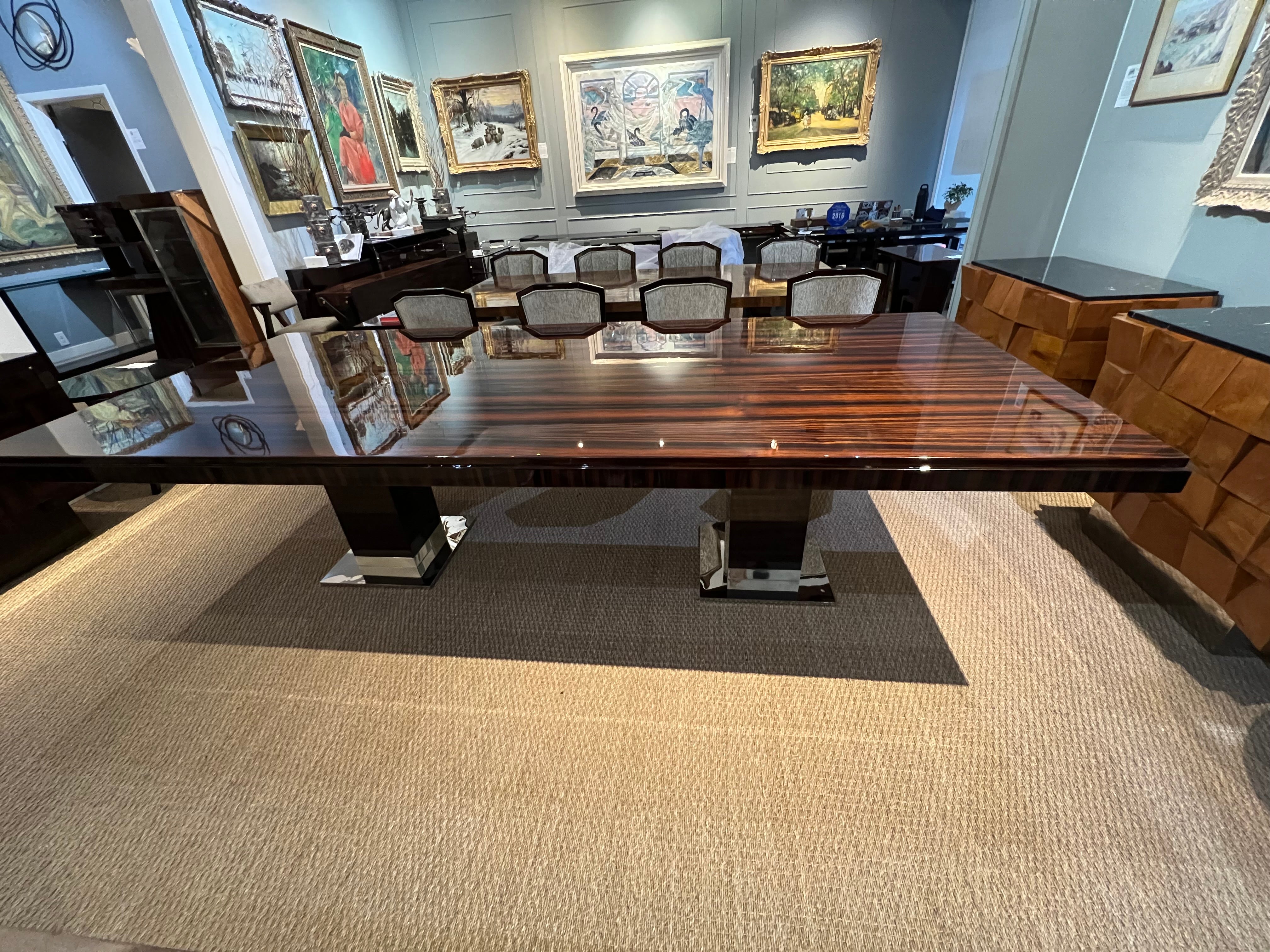 Grande table de salle à manger française de l'époque Art déco en bois de Macassar. Le plateau de la table présente de magnifiques veines de bois. La table repose sur 2 pieds rectangulaires et stables. Chaque pied est doté d'une base chromée. Le