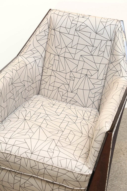 Frame of the chair is made from the rosewood. Chair was reupholstered in a light fabric with a geometric design. Upper edges of the chair has a wooden trimming for a better emphasis of chair’s trapezoid shaped back. Inner walls of the chair have