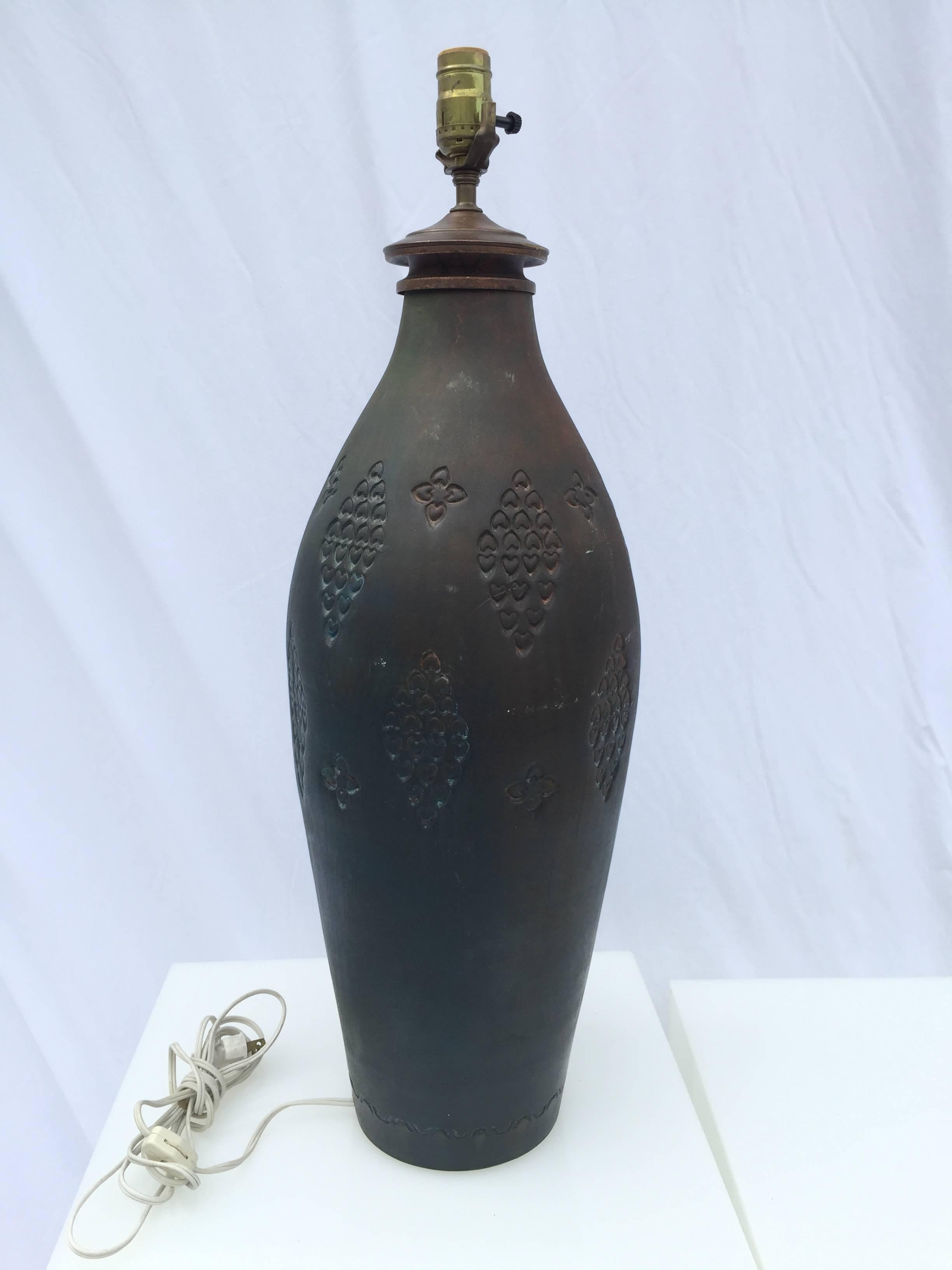 The deep, dark finish has burnished colors throughout the glaze. The impressed hearts are in various designs all-over the lamp. With a broad shoulder and slender foot. The base is in pastel colors and is inscribed base made Italy with a