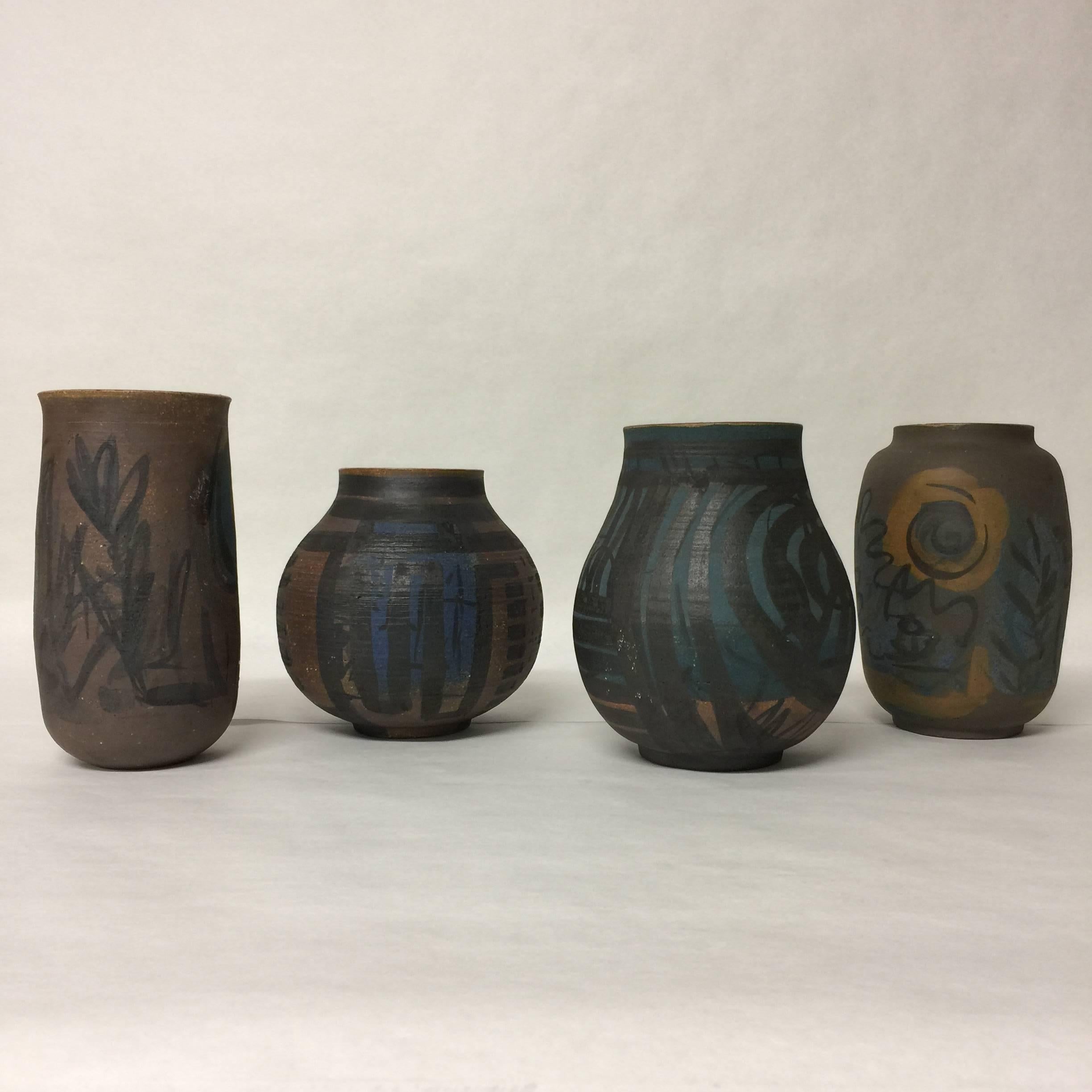 An assembled collection of four abstract hand-painted stoneware pottery vessels or vases with the outer surface being matte and the inner surface having a glaze. Measurements in order from left to right: Tallest 8.25