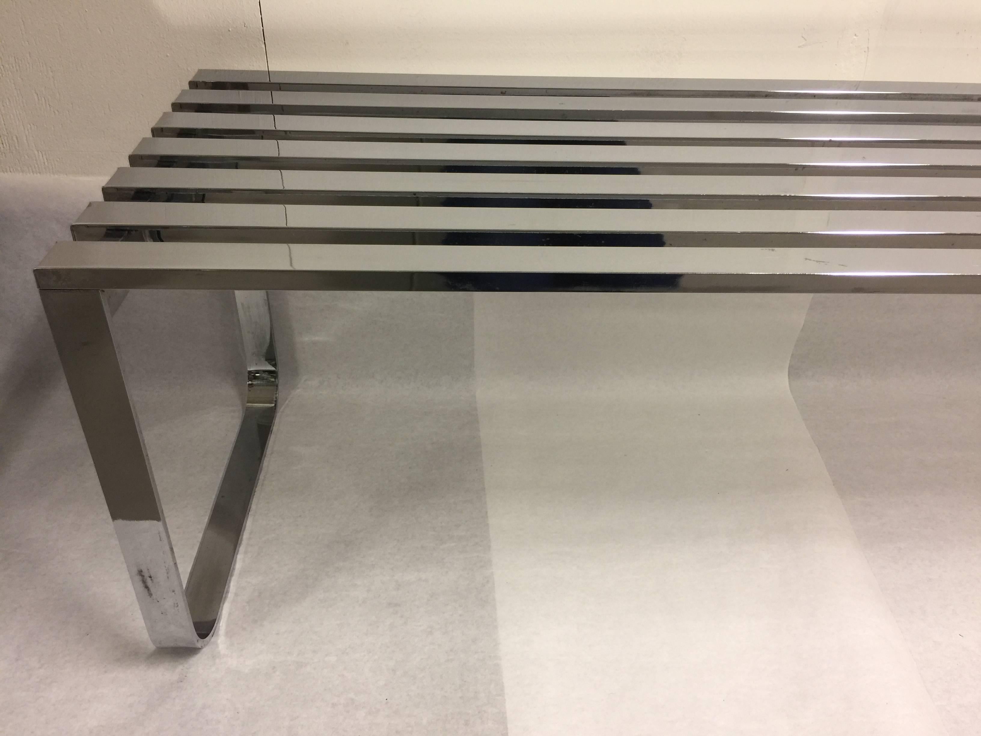 The perfect bench or coffee table. This vintage circa 1970s chrome-plated flat bar slat bench embodies chic. Squared legs with rounded corners support each side. Minimalist and modern.
