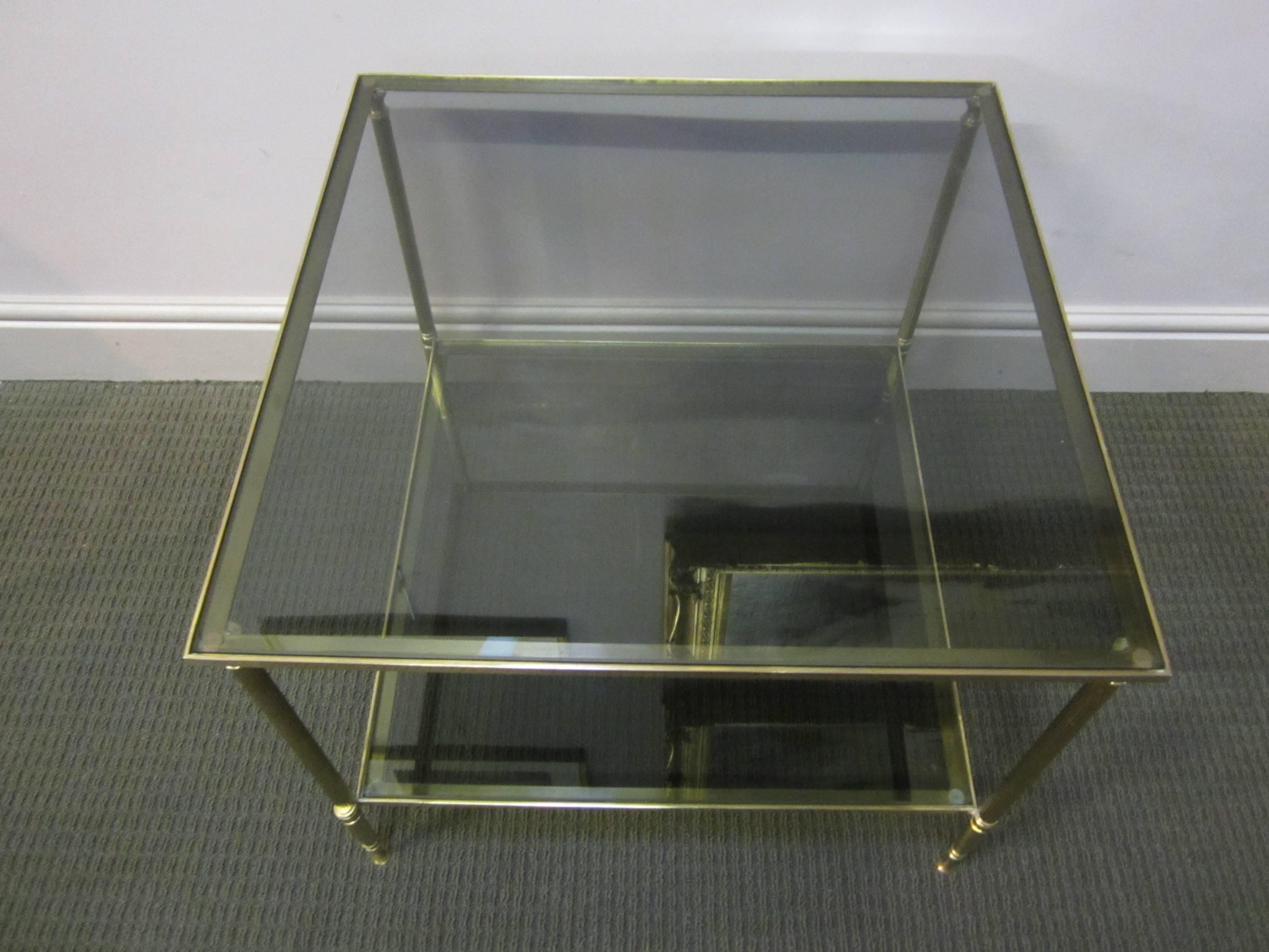 French gilt bronze side table, the two tiers enclosing smoked glass, the legs of fluted columns and turned cushion feet