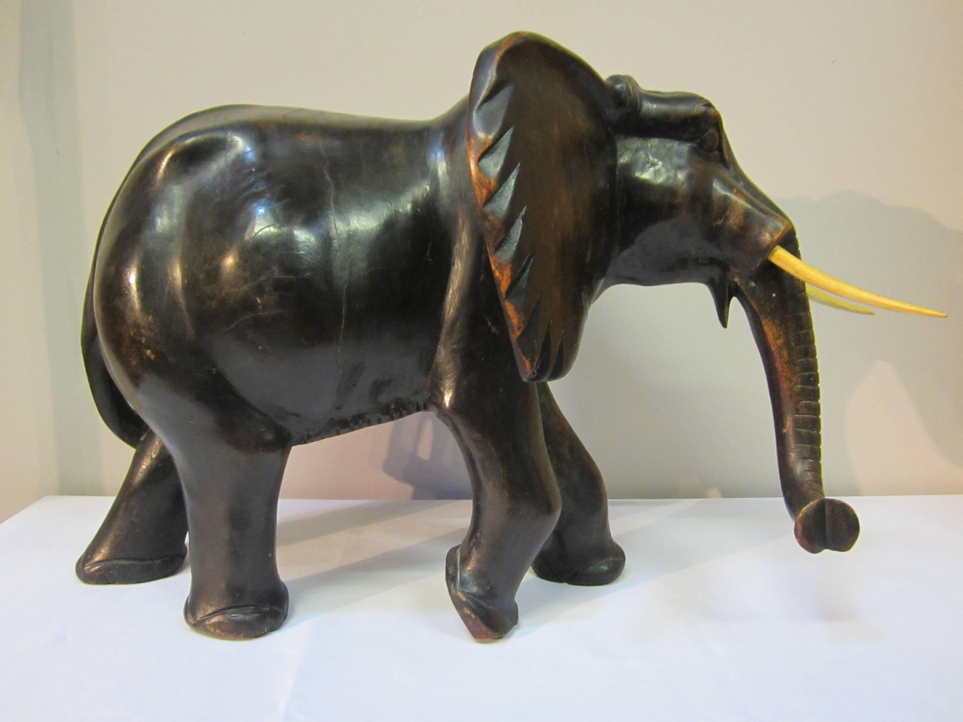 Solid teak elephant model in moving pose with swaying trunk, the well detailed body contrasting well with the maple wood tusks.
Good proportioned example with great patina.