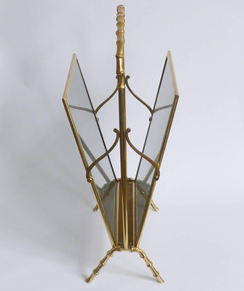 A chic 1950s Mid-Century design magazine holder from Maison Baguès made of brass with smoked glass panels. The brass frame features scrolls motifs and faux bamboo arching handle and feet. The glass panels have no chips and no