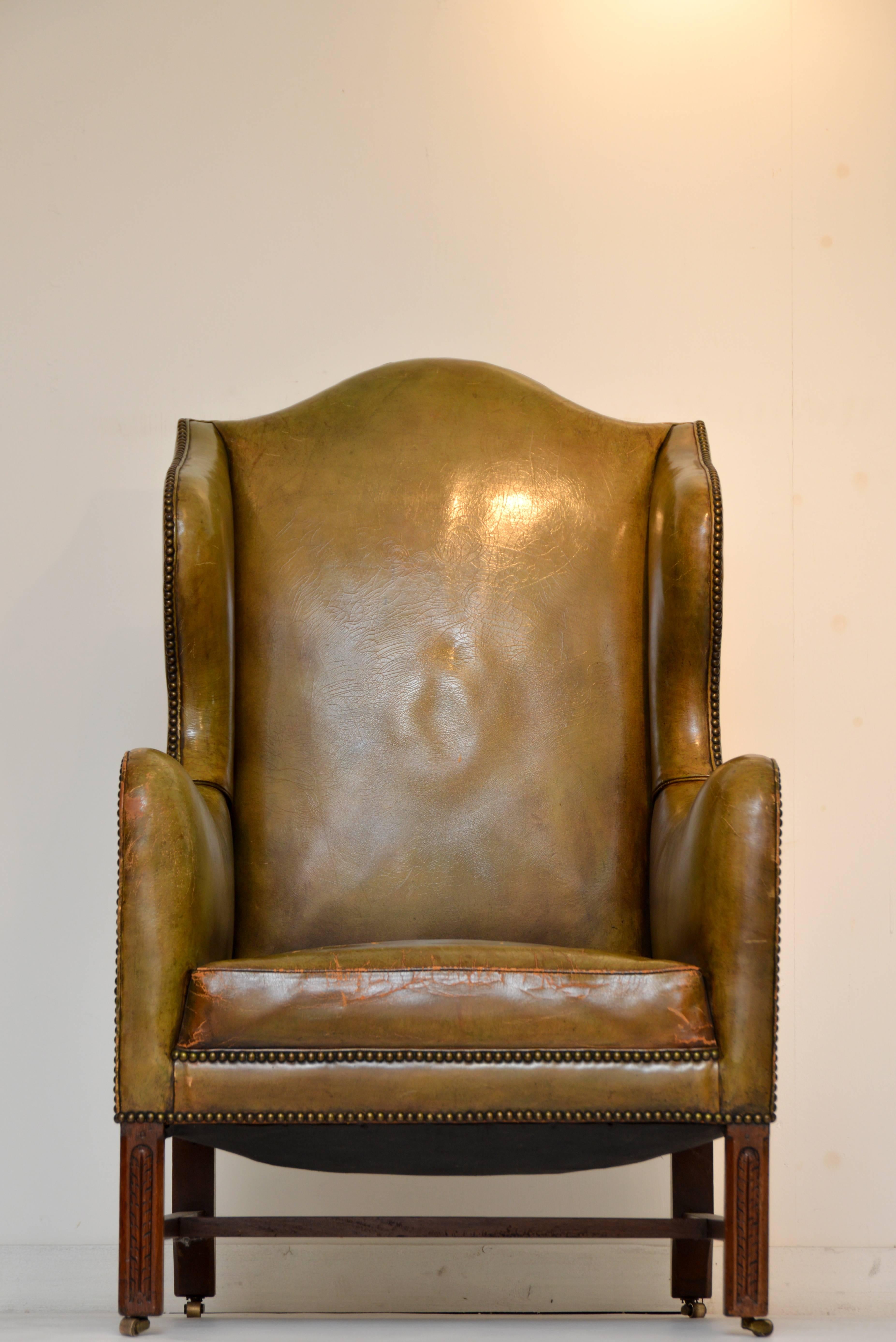 Vintage green leather wing chair with the right amount of rich patina which can only be created from many years of use.