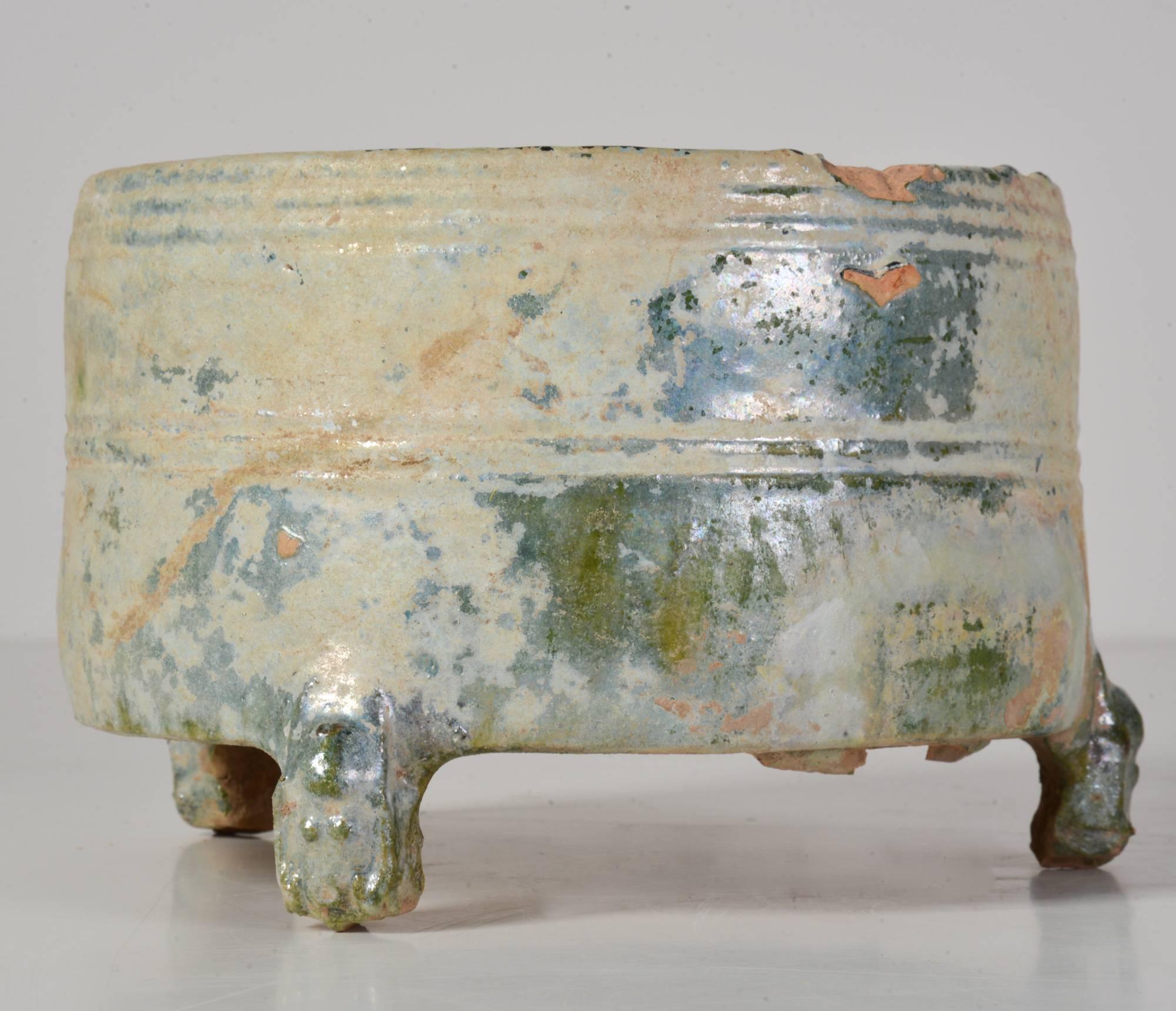 A wonderful Han dynasty (206 BC-200 AD) incense burner. The circular body set upon three bear shaped legs and is covered in heavy leaded green glaze. The body is shaped with bands of incised rings. The glaze has degraded from centuries of burial,