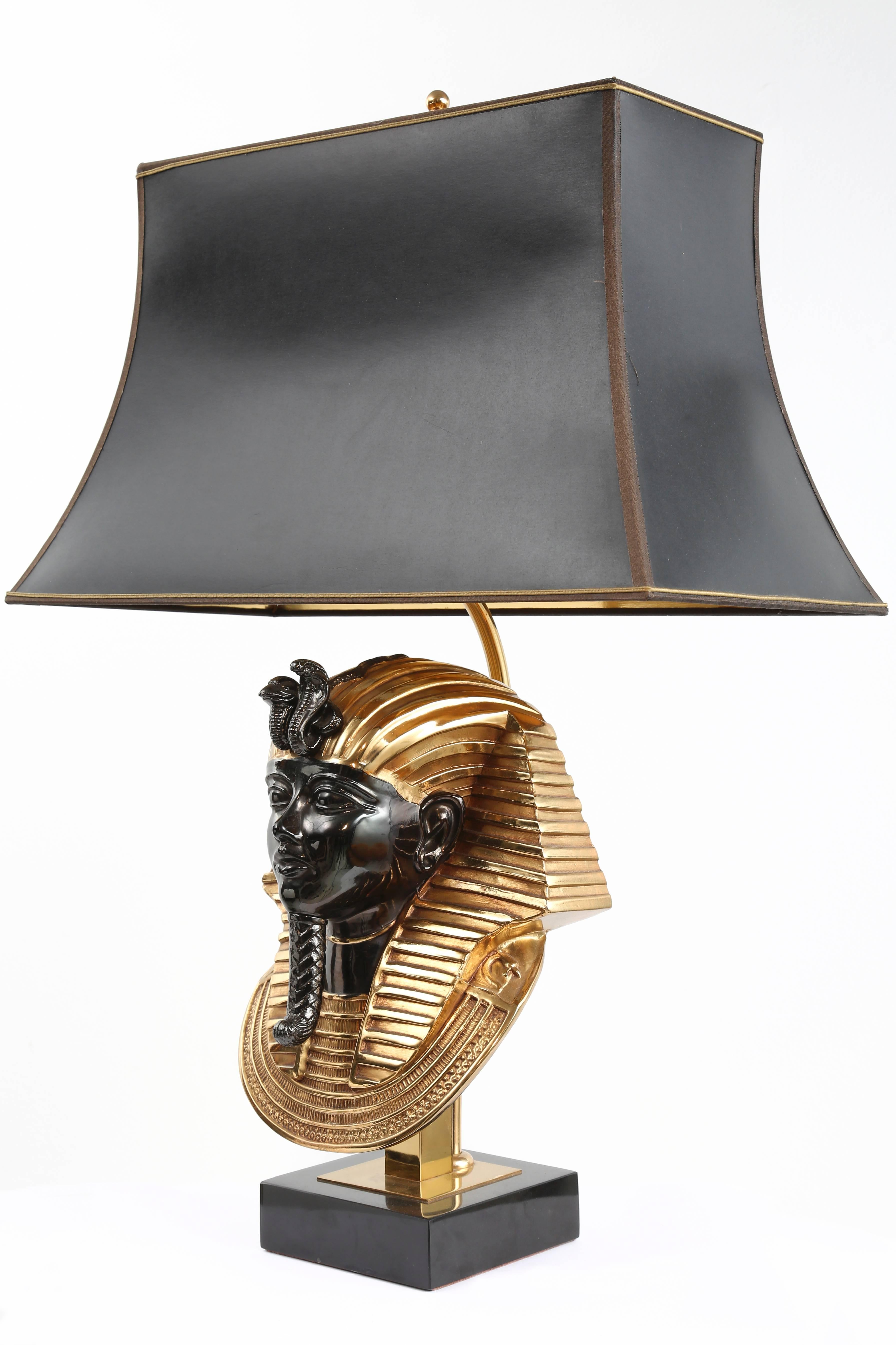 A pair of Egyptian revival Pharaoh head table lamps, model Faro, designed by Maison Jansen for Deknudt, Belgium, 1970s. The lamp is made from 24-karat gold-plated brass and bronze on black marble base, with original shades. Creates a soft light.