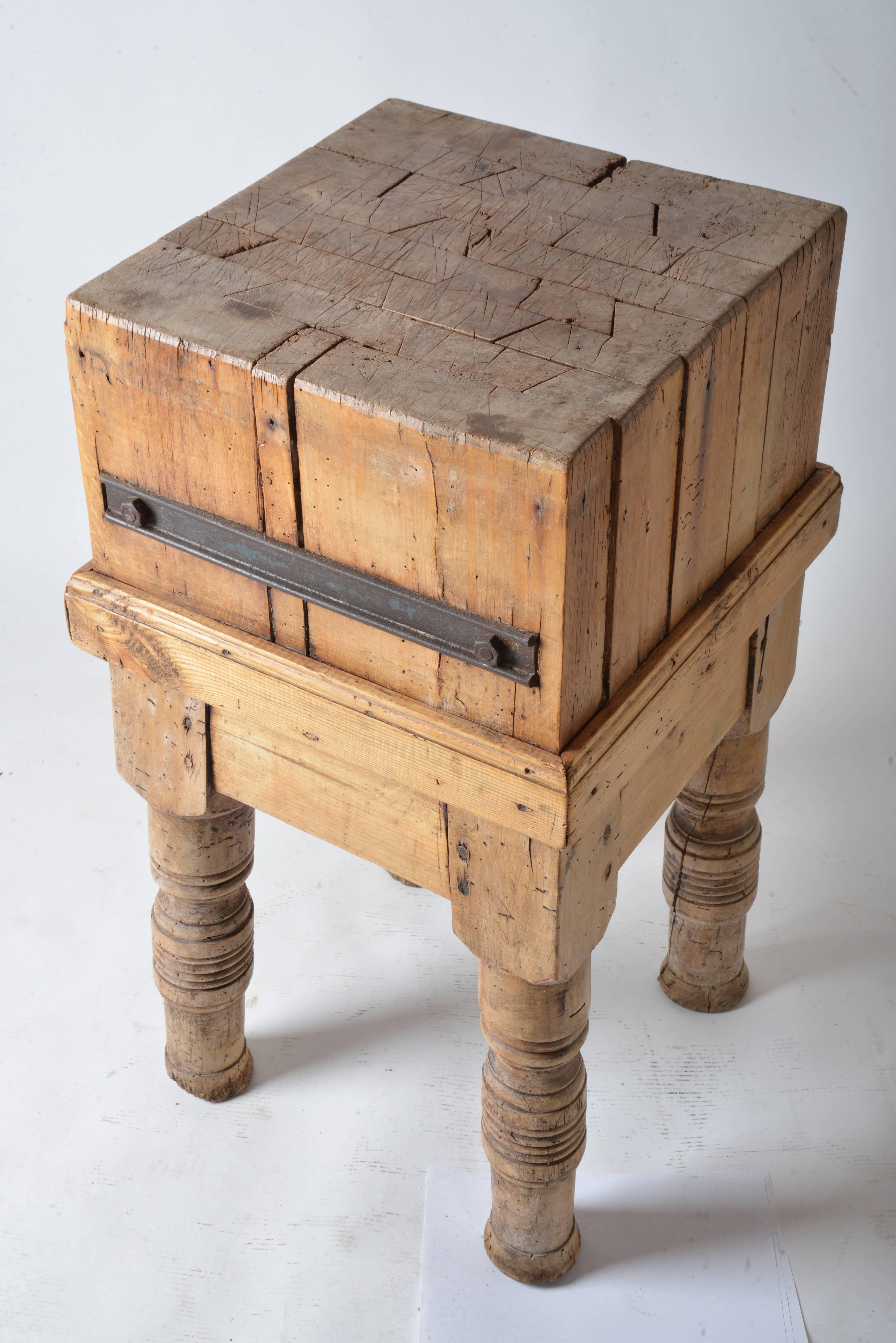 A French billot de boucher (butcher block) on four legged stand. The thick top has a distressed and vintage look from decades of use. The wood has a wonderful patina. Steel corner braces.